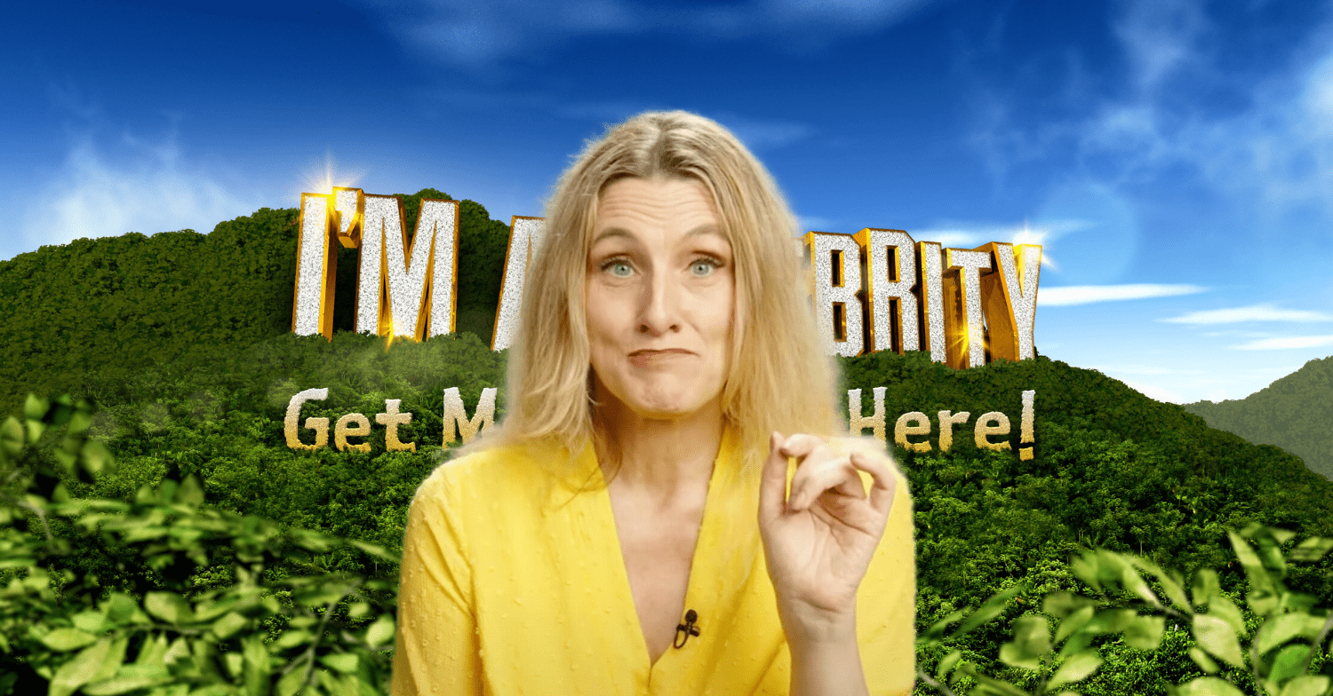 Grace Dent in a yellow outfit stood in front of the I'm A Celebrity logo