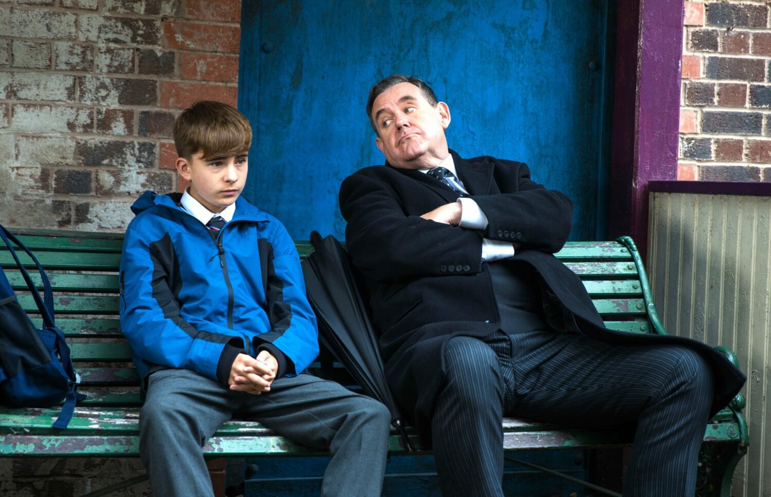 Liam looks sad as George offers wisdom on a bench in Coronation Street