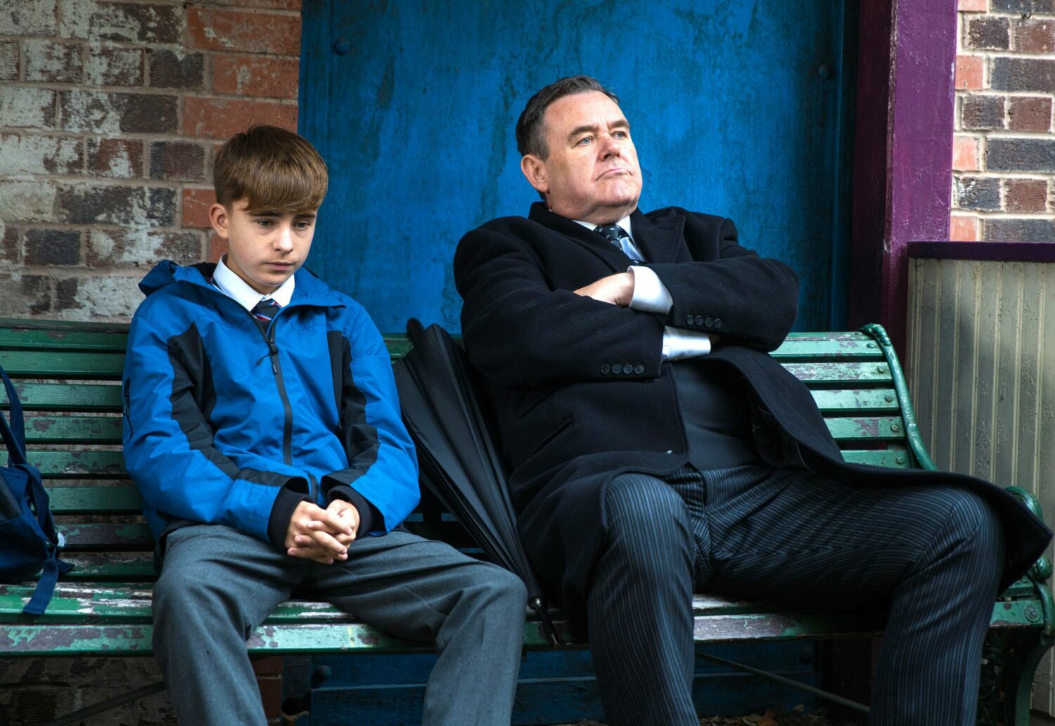 Coronation Street's Liam and George are sitting on a bench outside together
