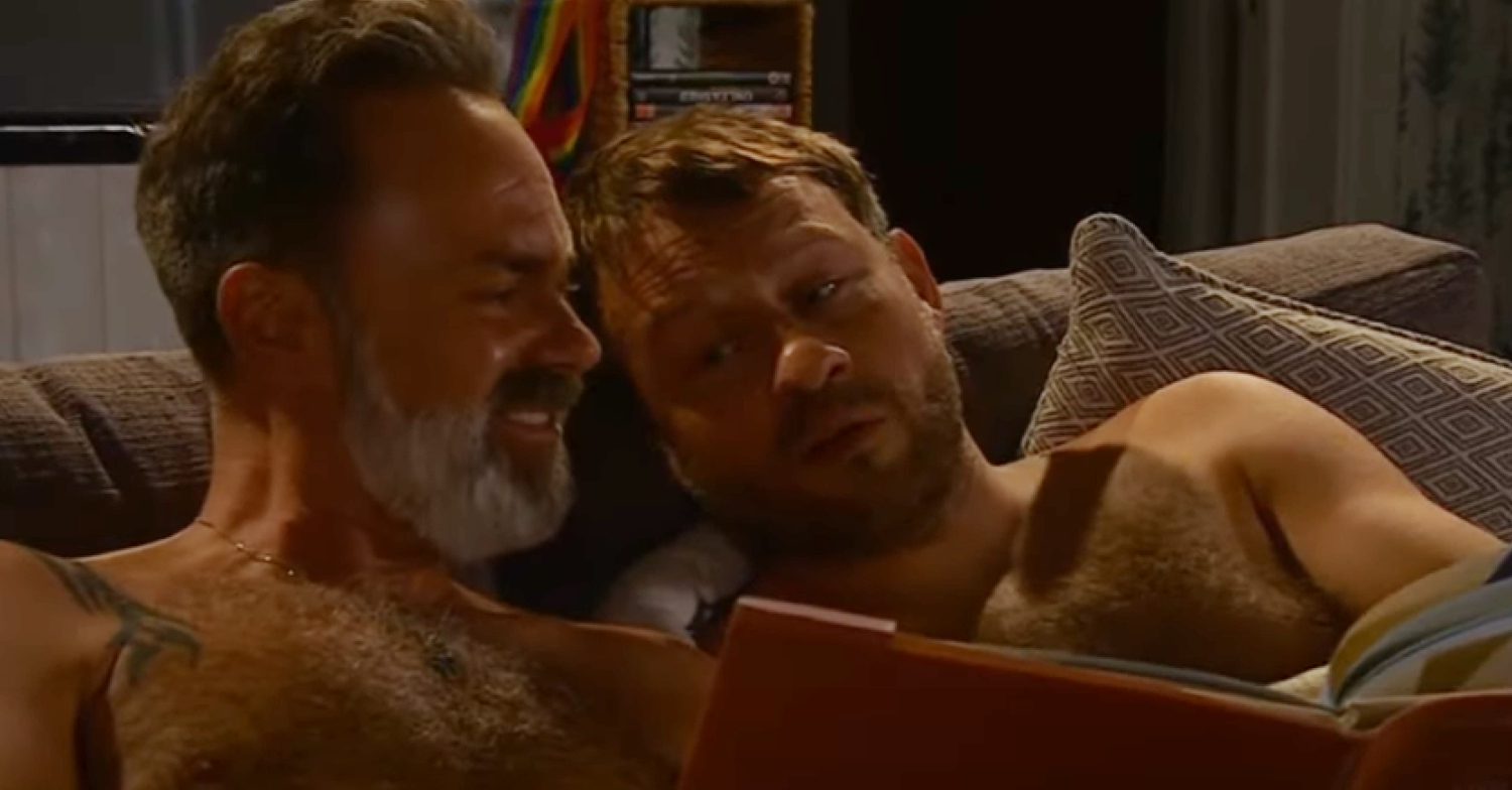 Coronation Street's Billy and Paul are reading a book together, topless on the sofa