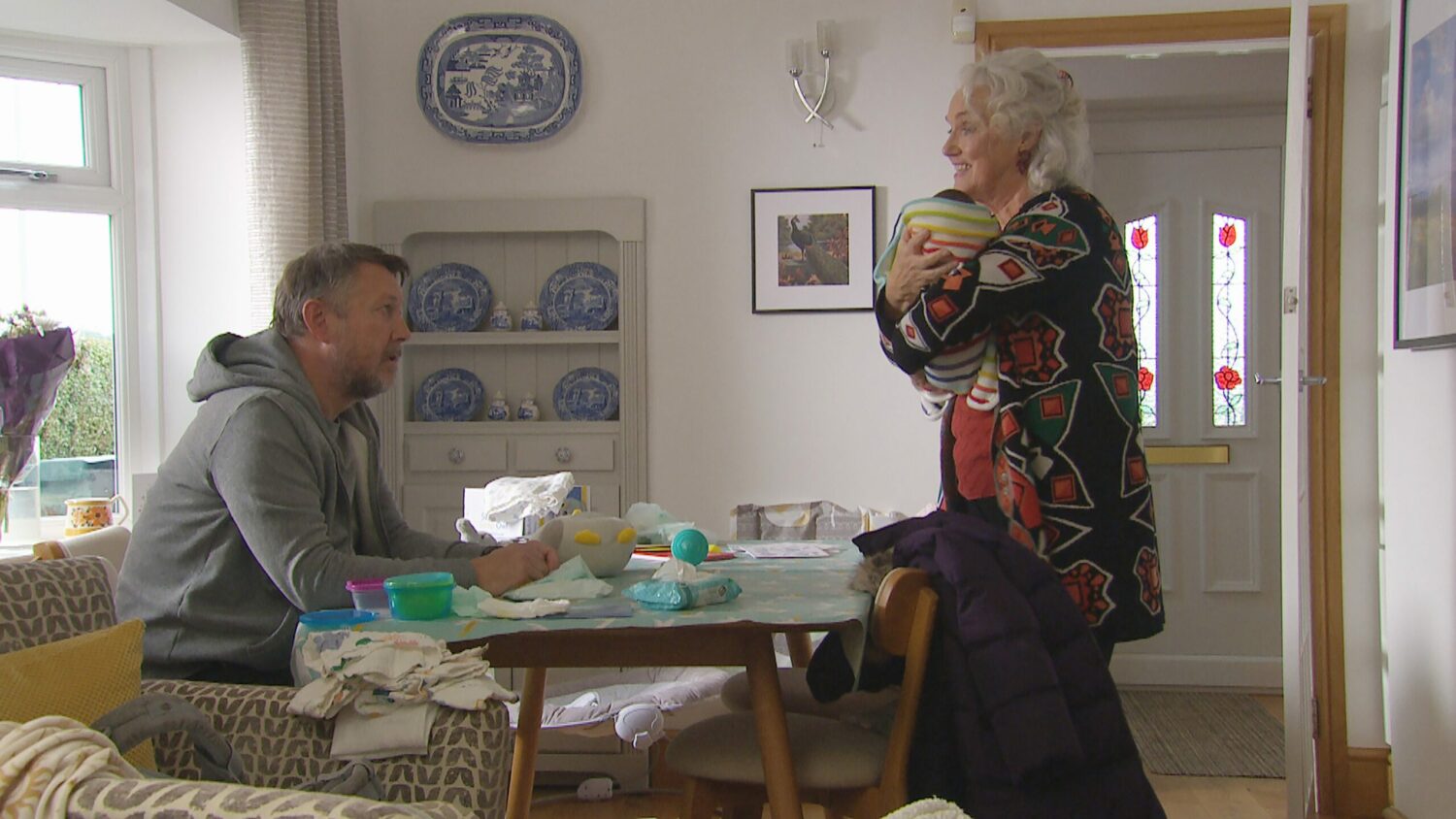 Mary holds baby Ivy while Gus looks on in Emmerdale