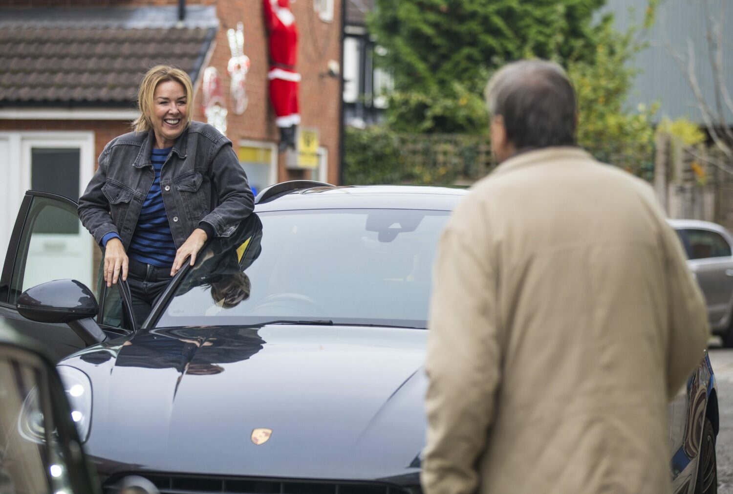 Cassie and Roy standing next to a Porsche on Corrie