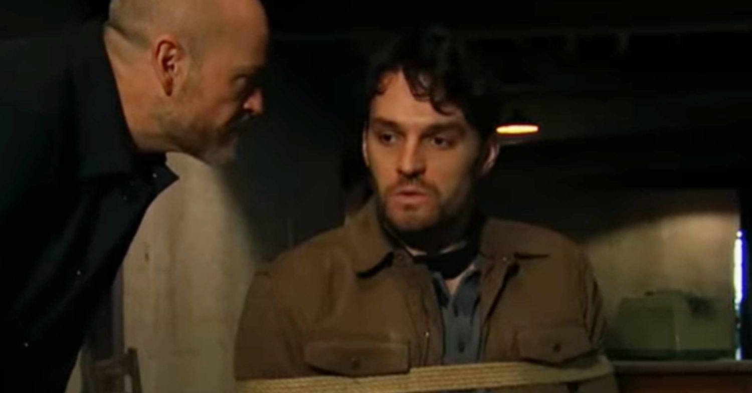 Emmerdale's Mack is tied up to a chair as Harry leans over him