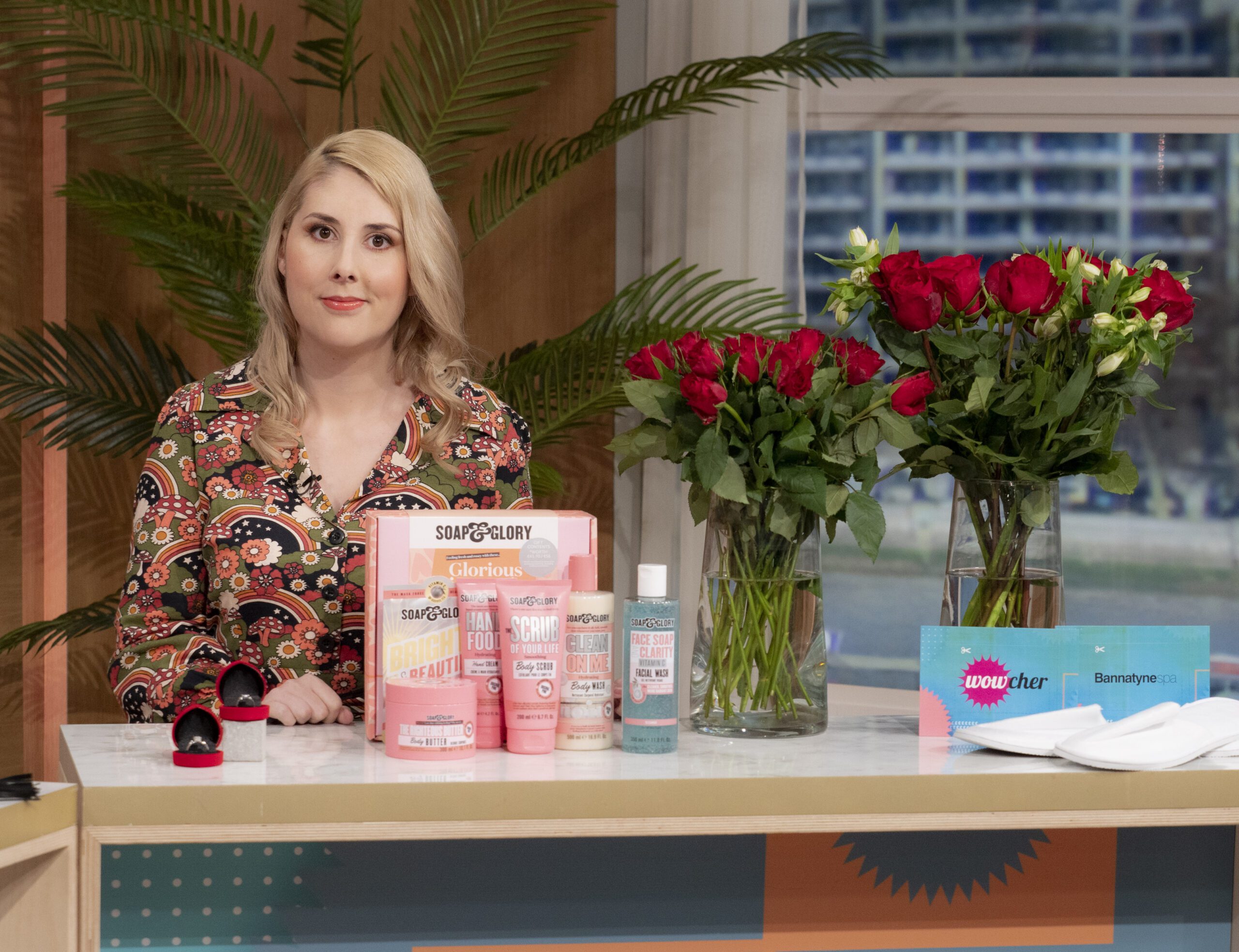 This Morning star Holly Jay-Smith stands in front of products and a table of roses with a small smile.