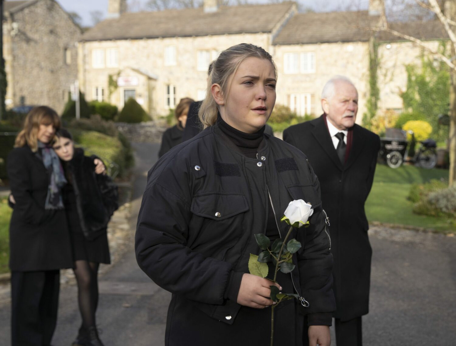 Cathy sobs as she holds a white rose at Heath's funeral in Emmerdale