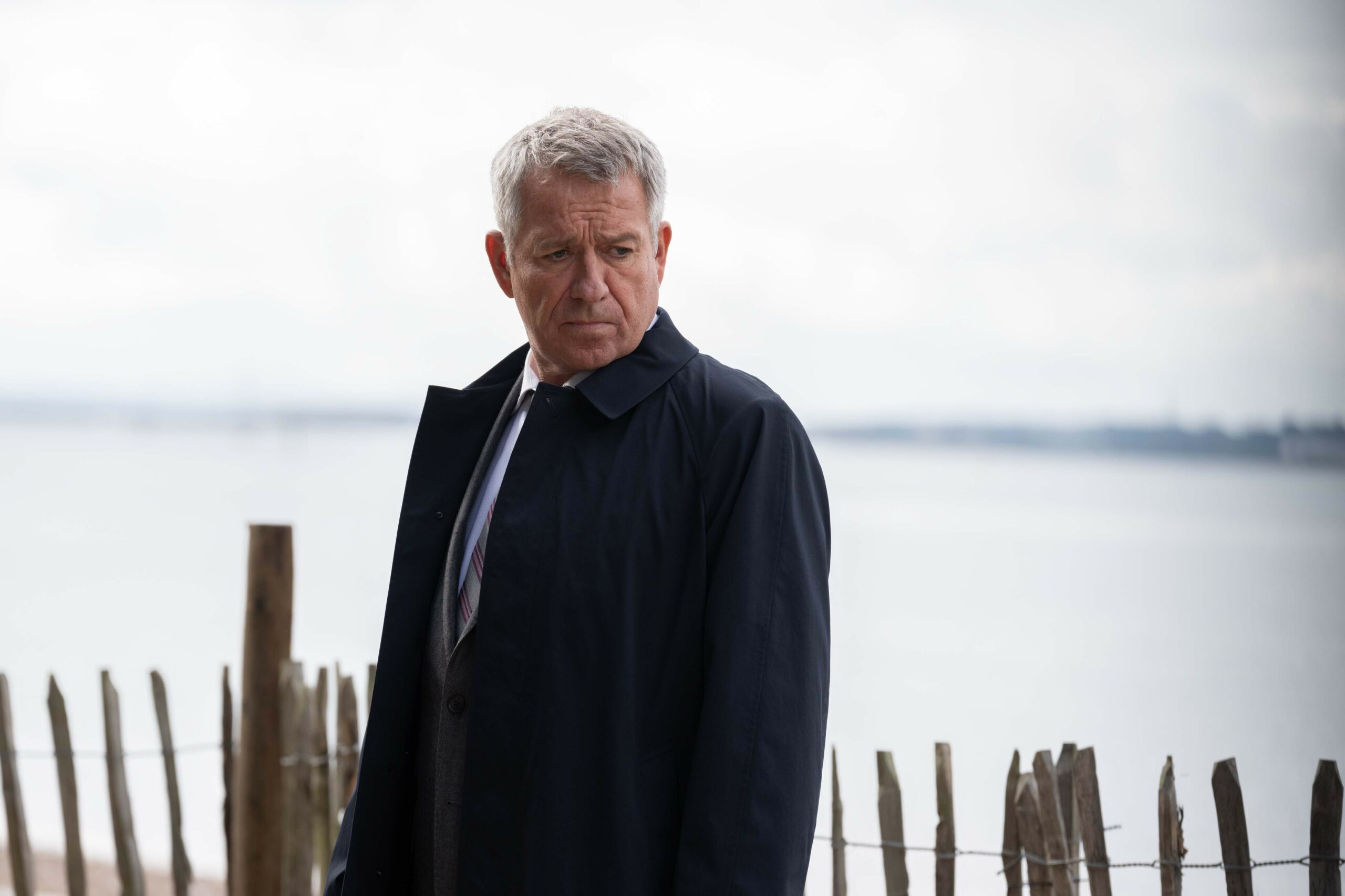 Sean Pertwee looks moody on a beach in character as DI John Flynn in Silent Witness