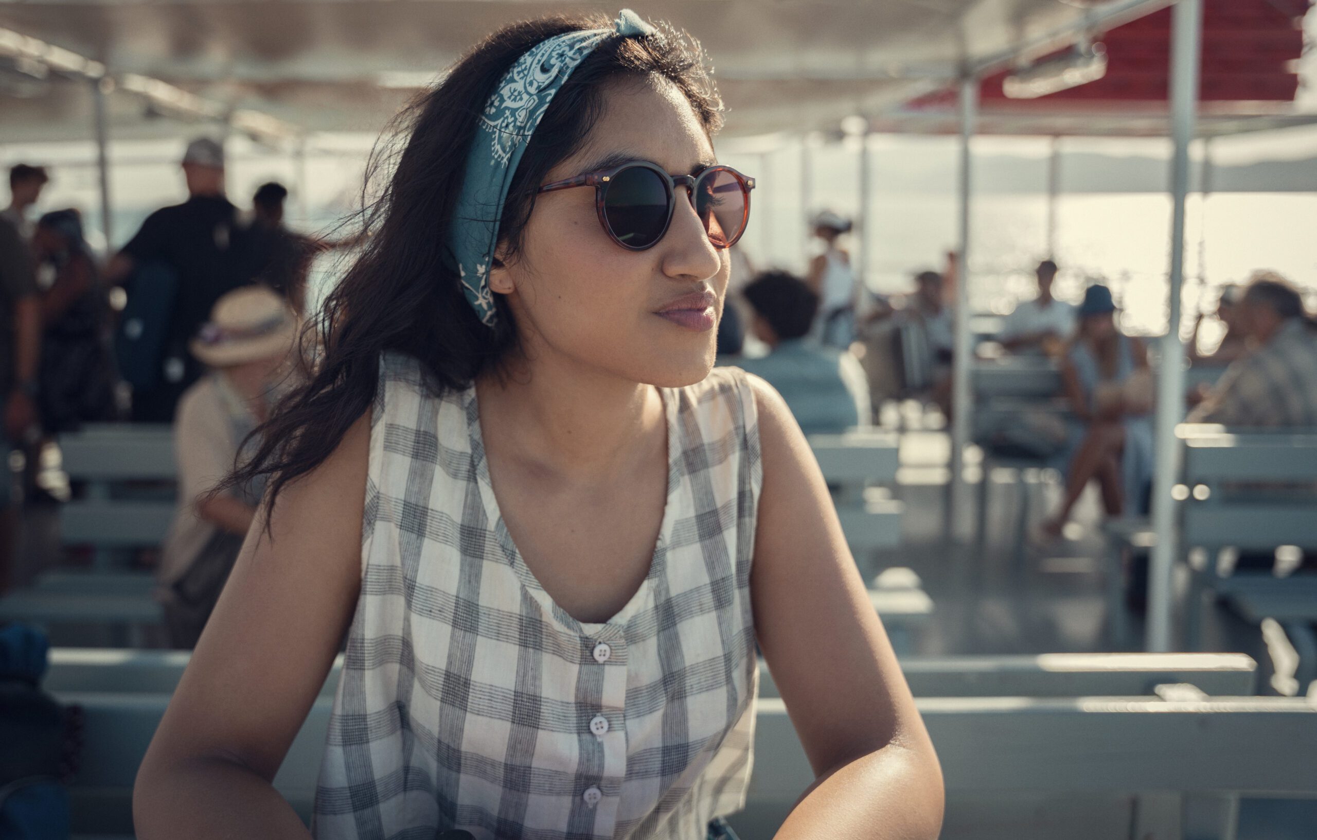 Ambika Mod as Emma Morley in One Day, wearing sunglasses and looking out to sea from a boat