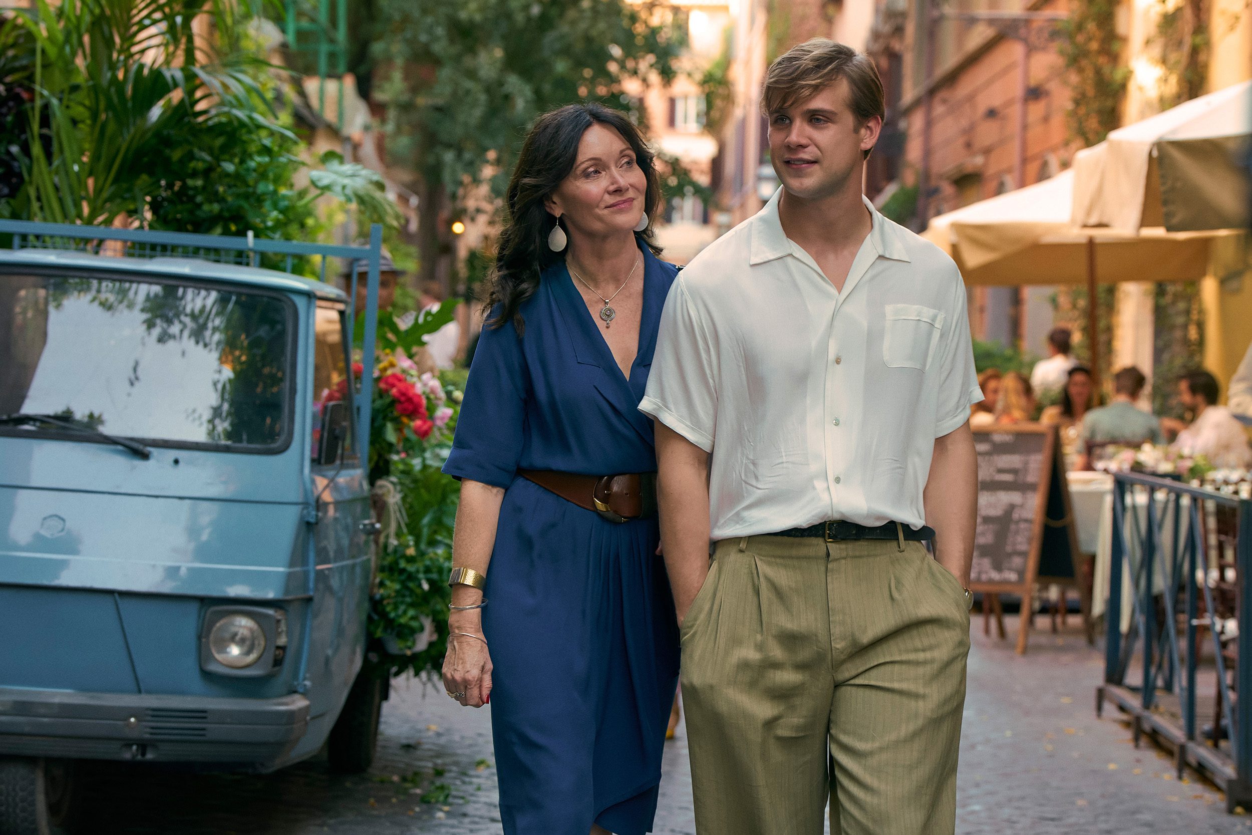 Essie Davis and Leo Woodall in character as mother and son Alison and Dexter, walking down a sunny Italian street in One Day