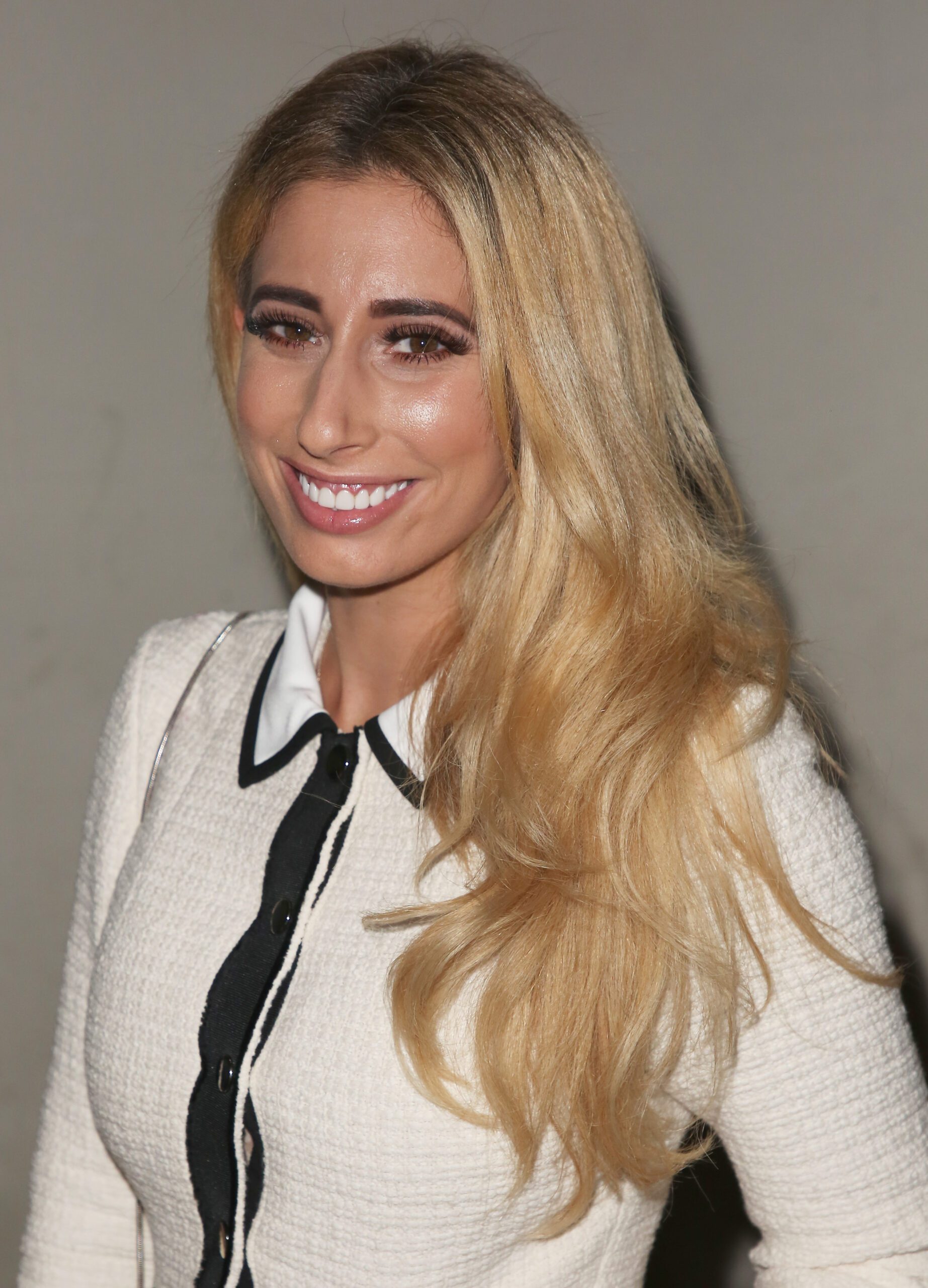 Blonde Stacey Solomon wearing a white blouse and smiling at the camera