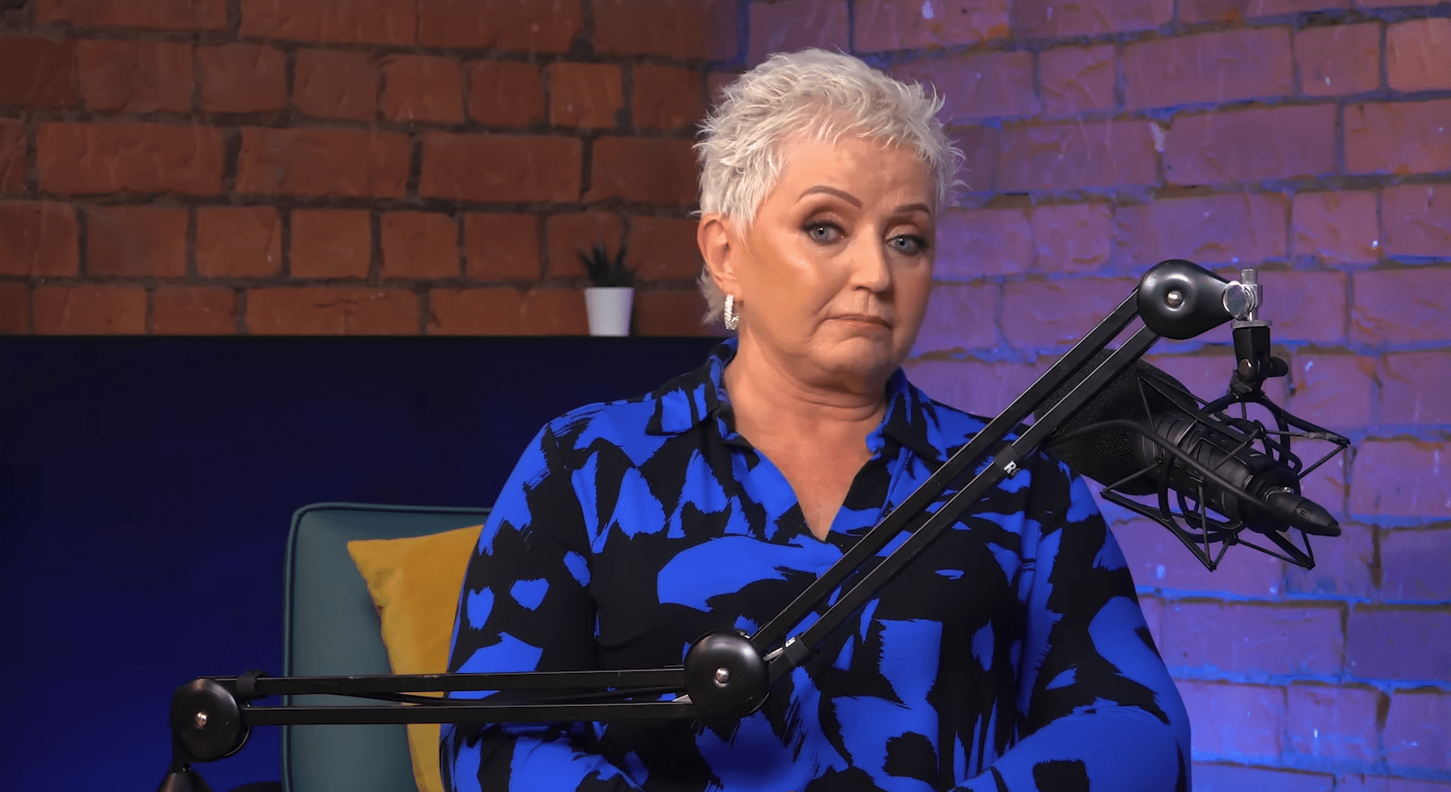 Linda Nolan speaking on a podcast in a blue shirt