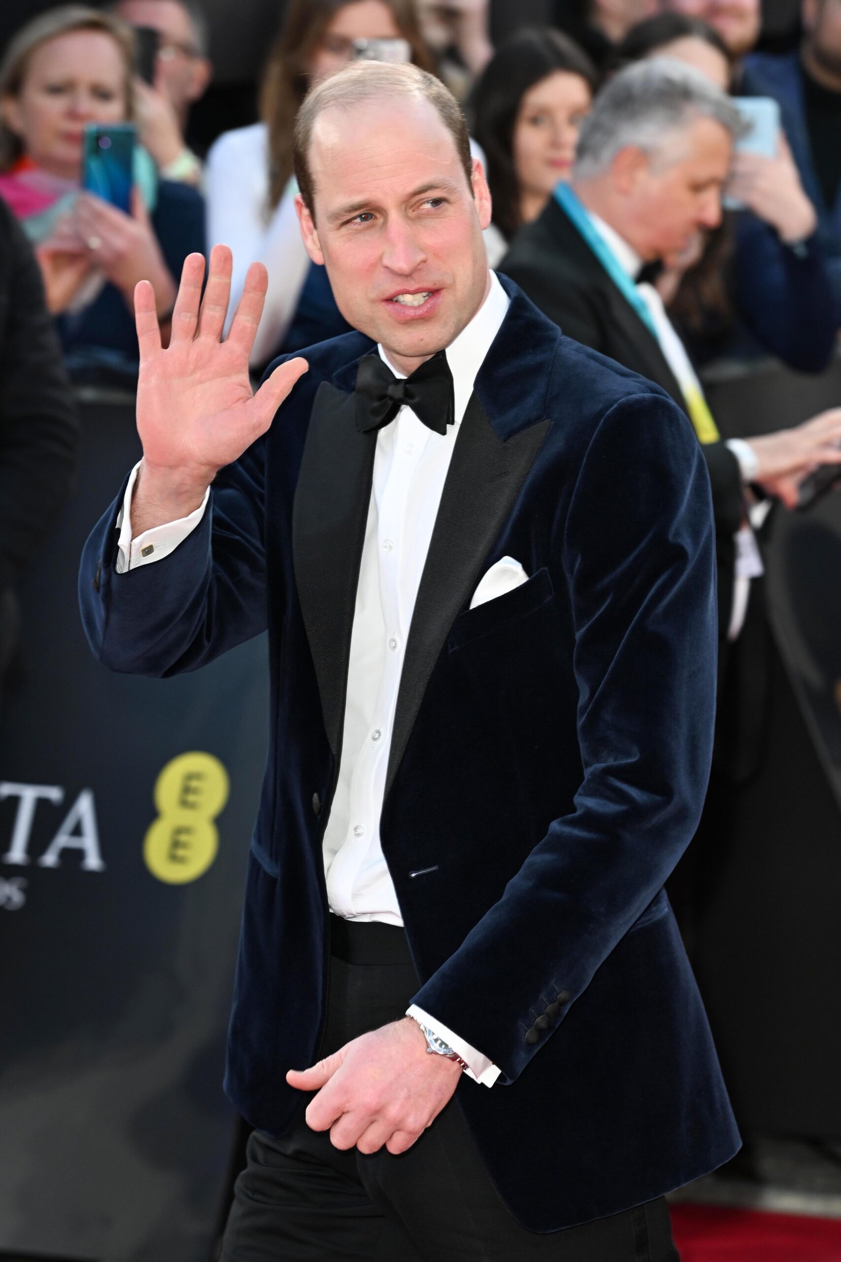 Prince William waving at camera in a velvet tuxedo at BAFTAs