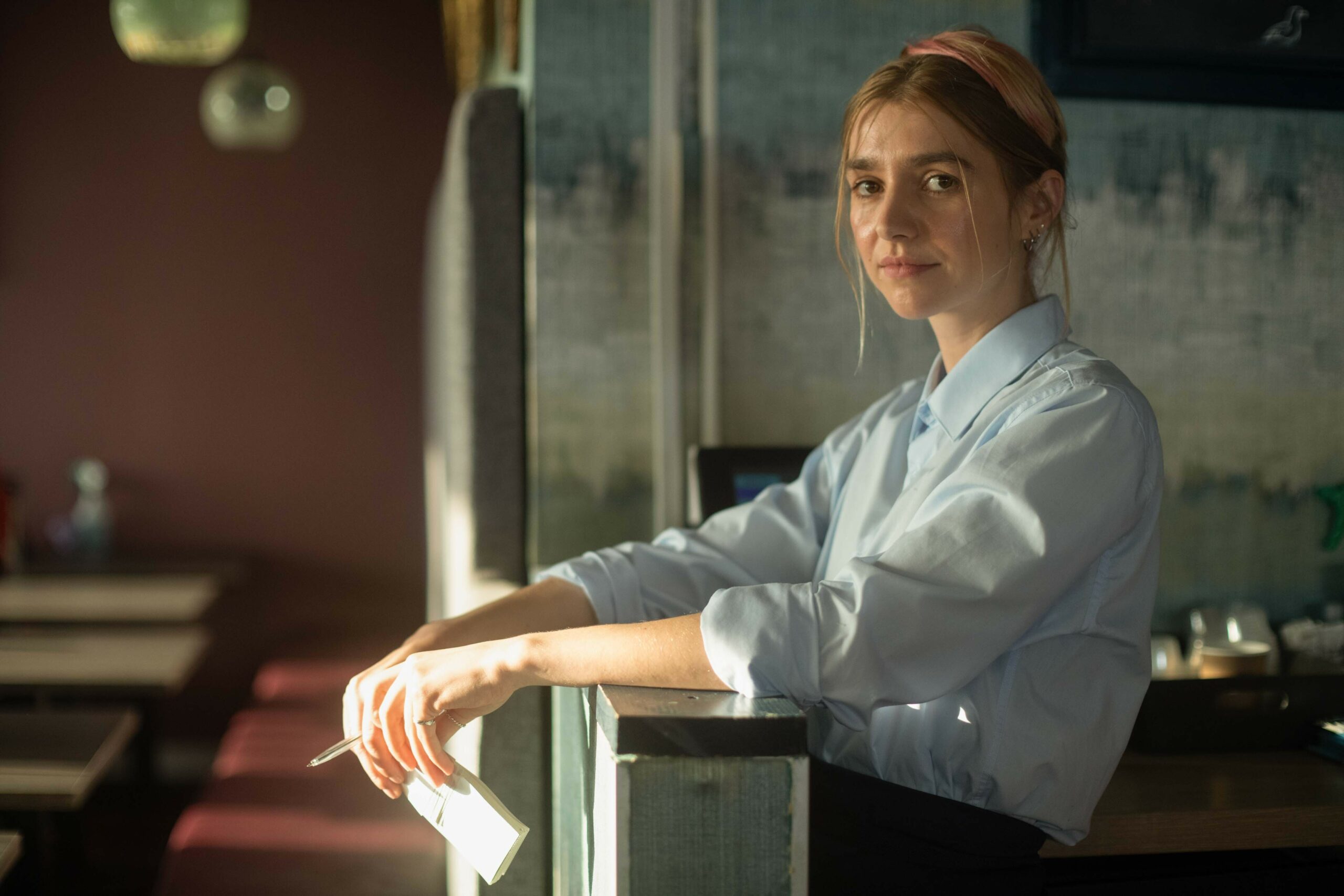 Maja Laskowska as Anna in The Way, with her arms on a ledge and holding paper