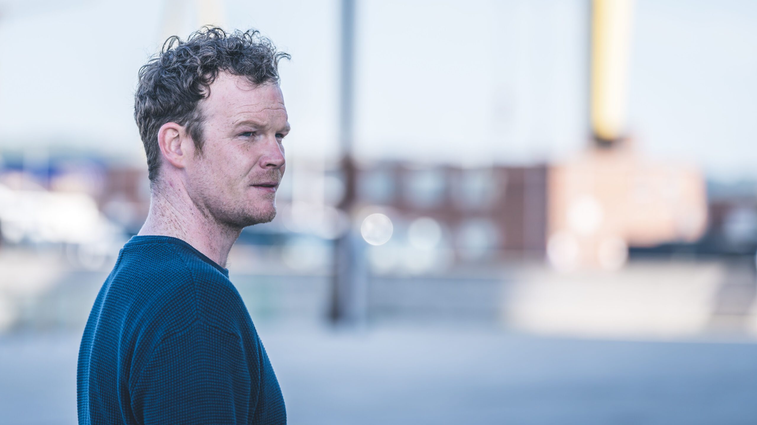 Seamus O'Hara as Lee Thompson , staring to the right in front of a blurred city