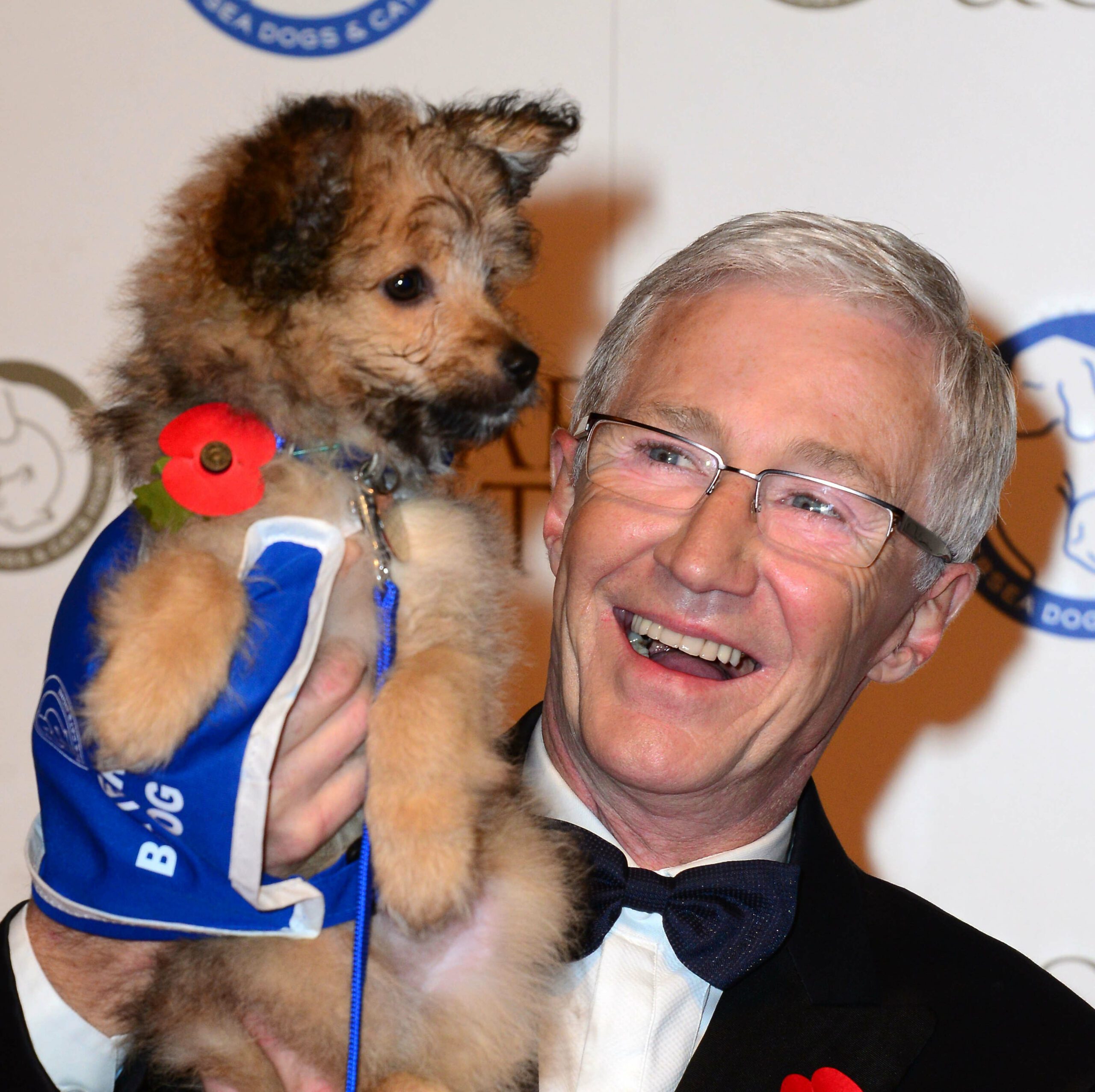 Paul O'Grady holding dog wearing a suit
