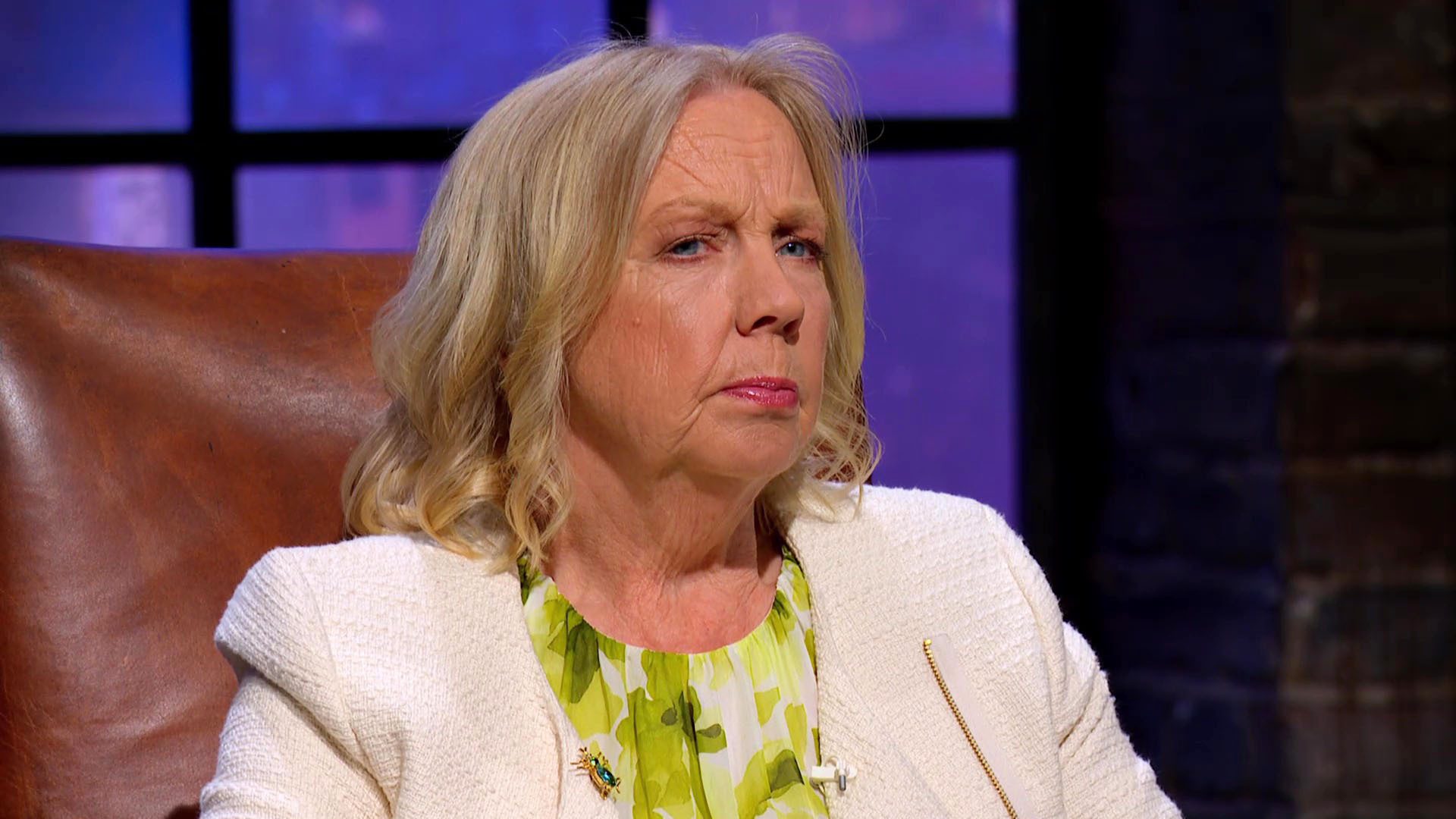 Deborah Meaden looking unimpressed wearing a white blazer and green shirt on Dragons' Den