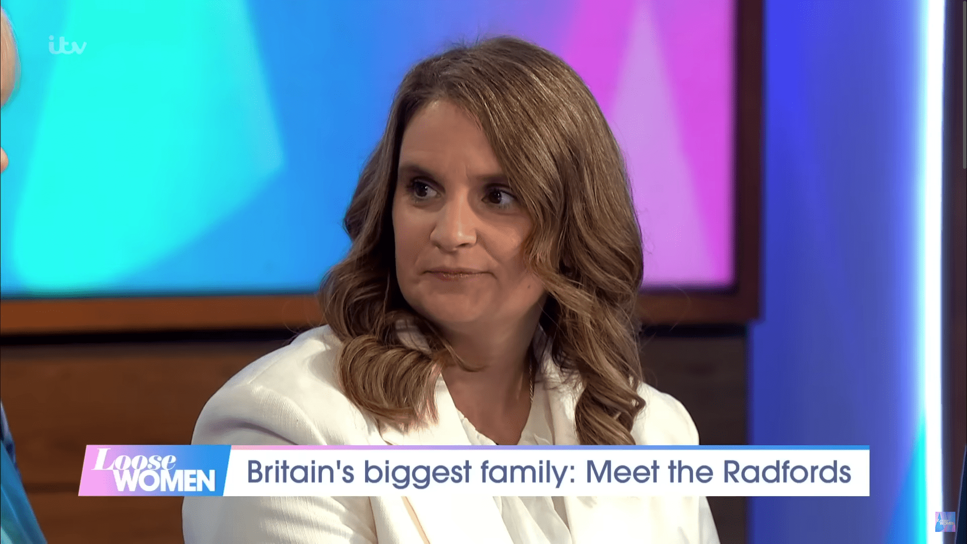 Sue Radford speaking to camera in a white jacket