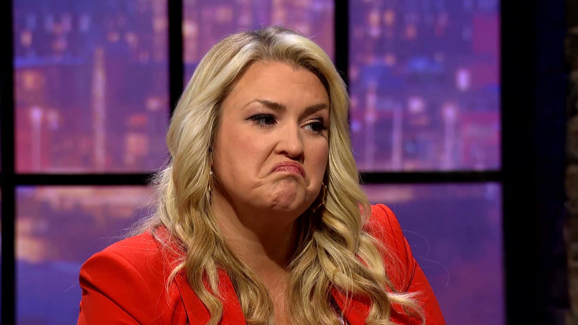 Sara Davies pulling a thoughtful face wearing red suit blazer