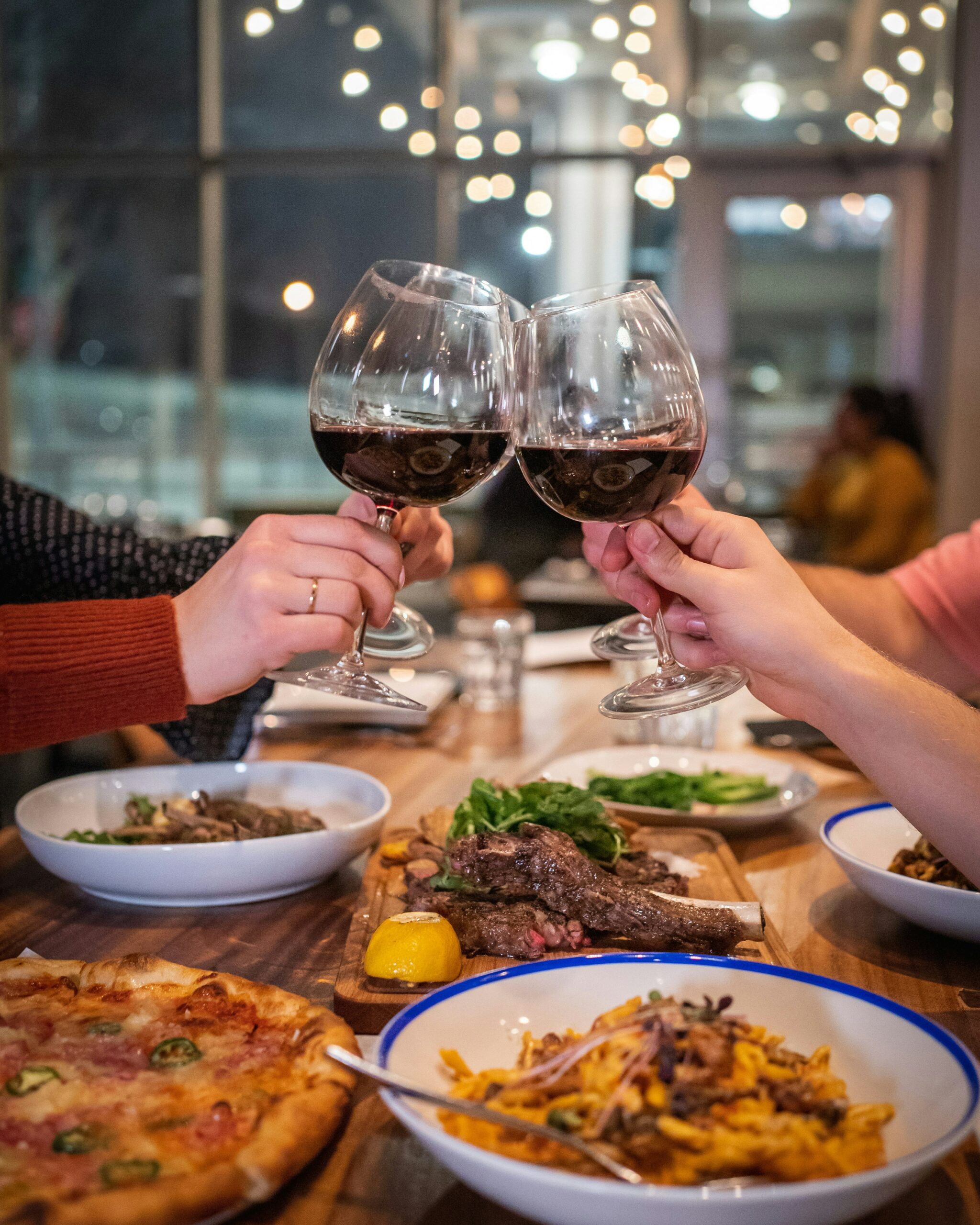 Two people with glasses of red wine saying cheers over dinner