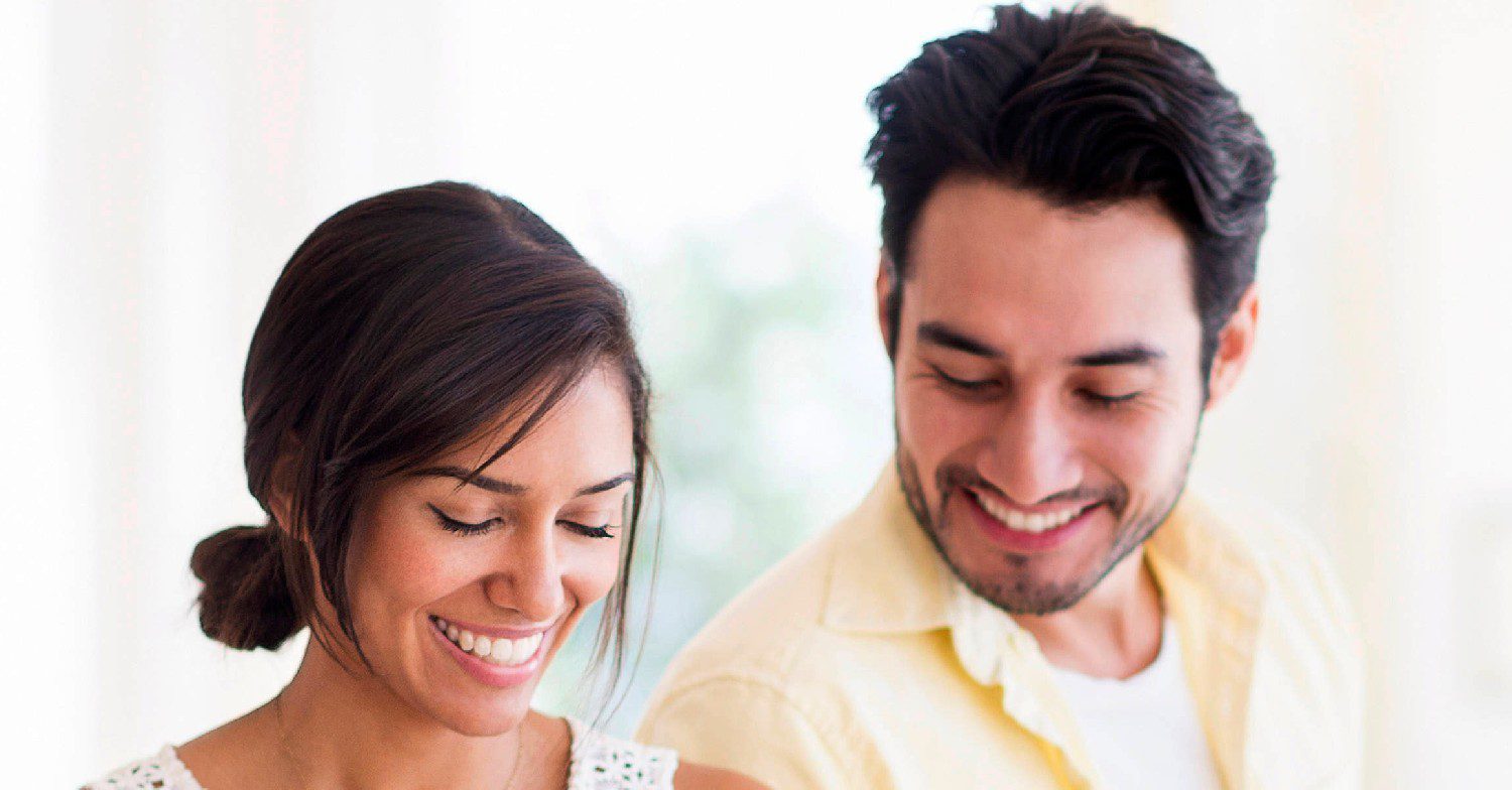 A woman and a man smiling in a sunny room