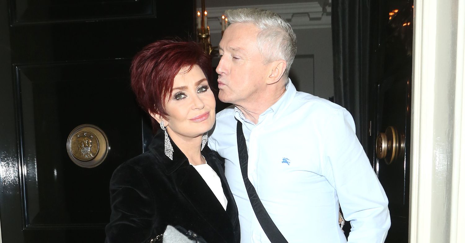 Sharon Osbourne smiling and Louis Walsh kissing her cheek
