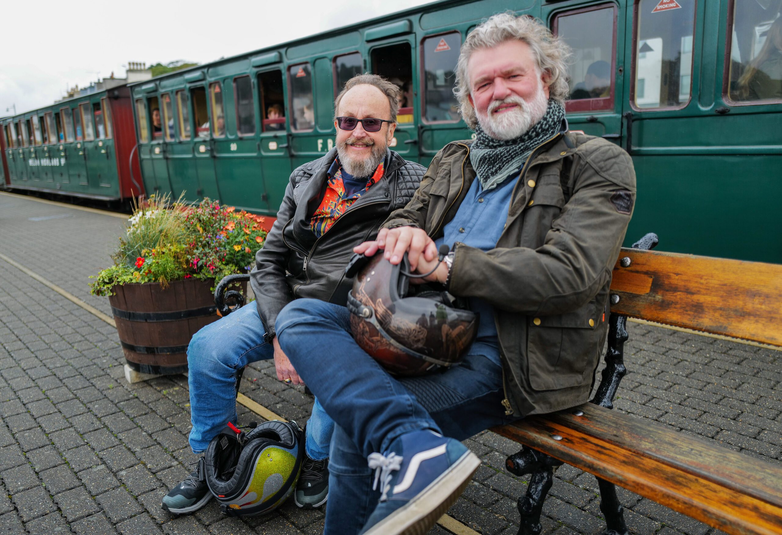 Hairy Bikers Dave Myers and Si King sitting in front of a train in Wales
