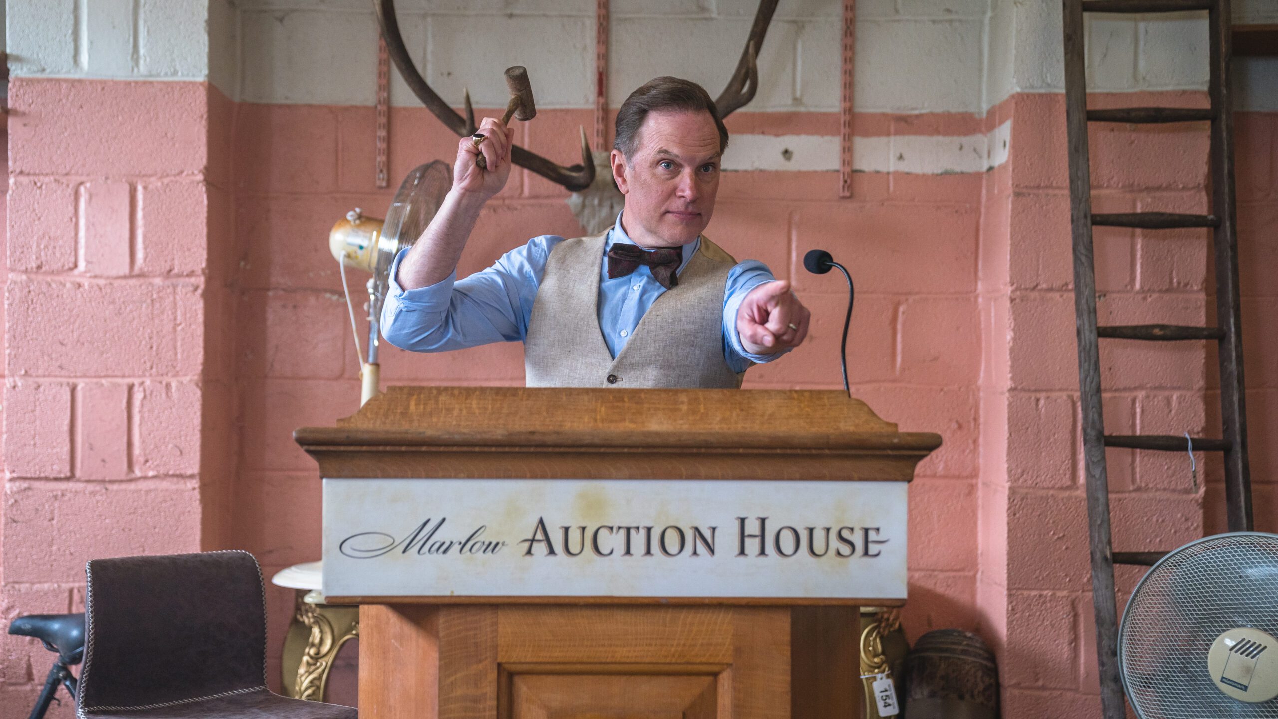Daniel Lapaine as Elliot Howard The Marlow Murder Club pointing a gavel 