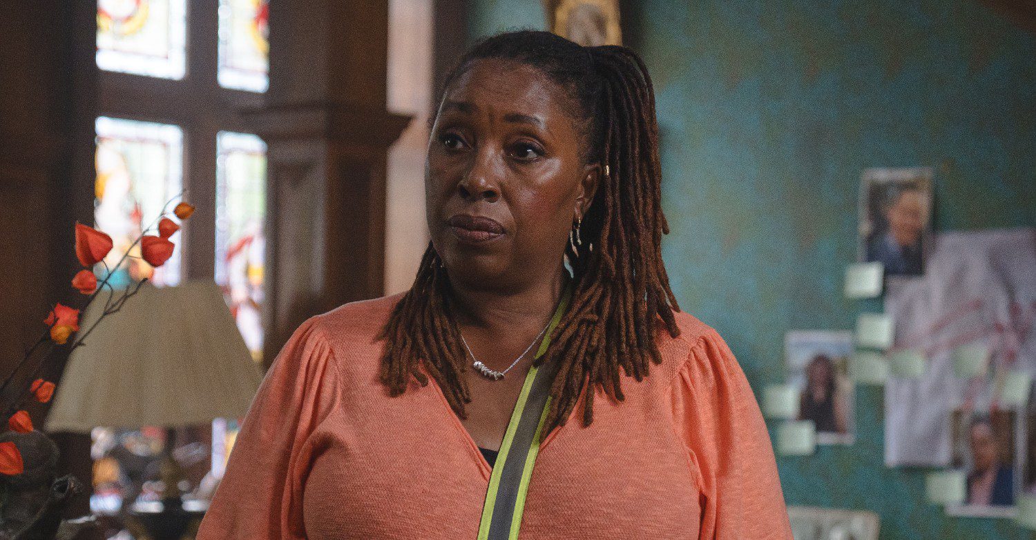 Jo Martin as Suzie Harris wearing an orange top in The Marlow Murder Club