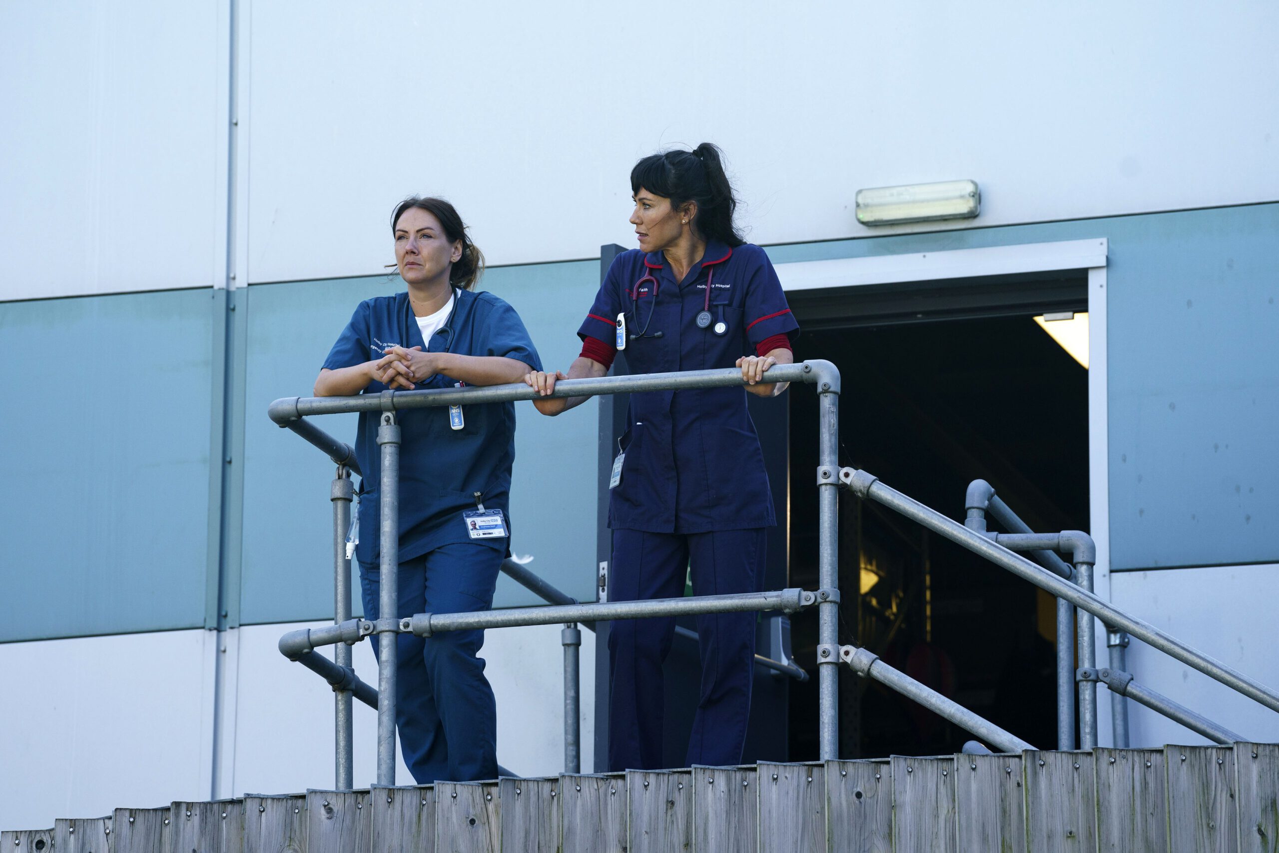 Stevie and Faith stand on a balcony looking stressed in Casualty spoilers