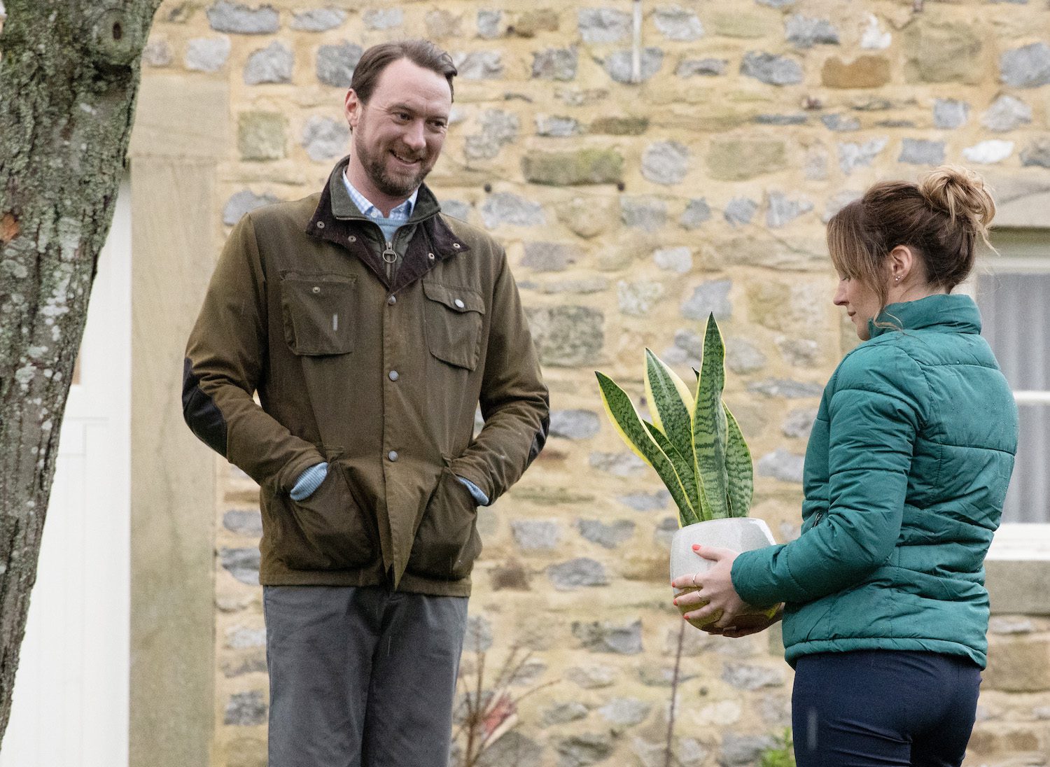 Emmerdale's Liam is smiling and talking to Ella outside as she holds a houseplant
