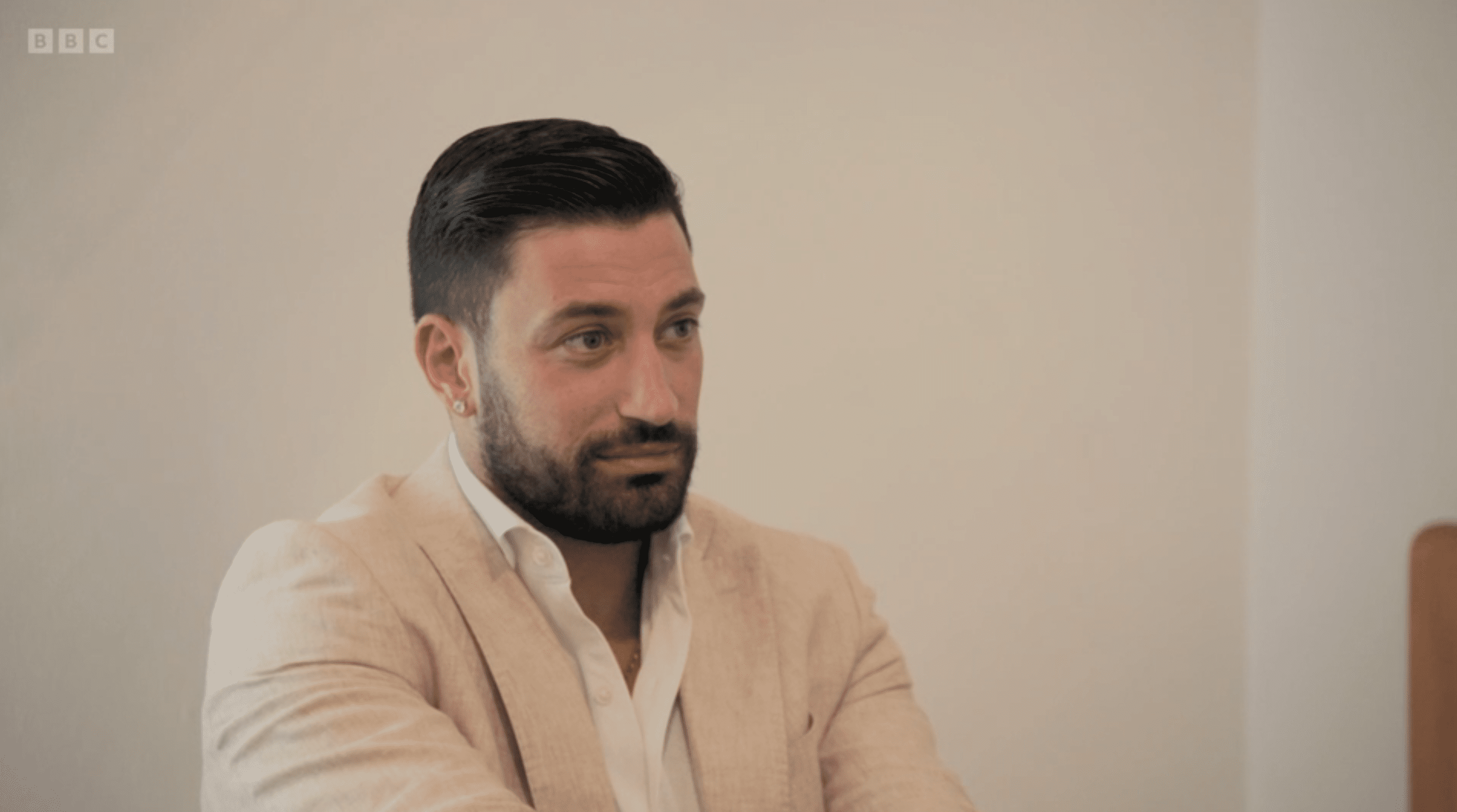 Giovanni in Anton and Giovanni's Adventures in Spain wearing a beige suit with a neutral expression