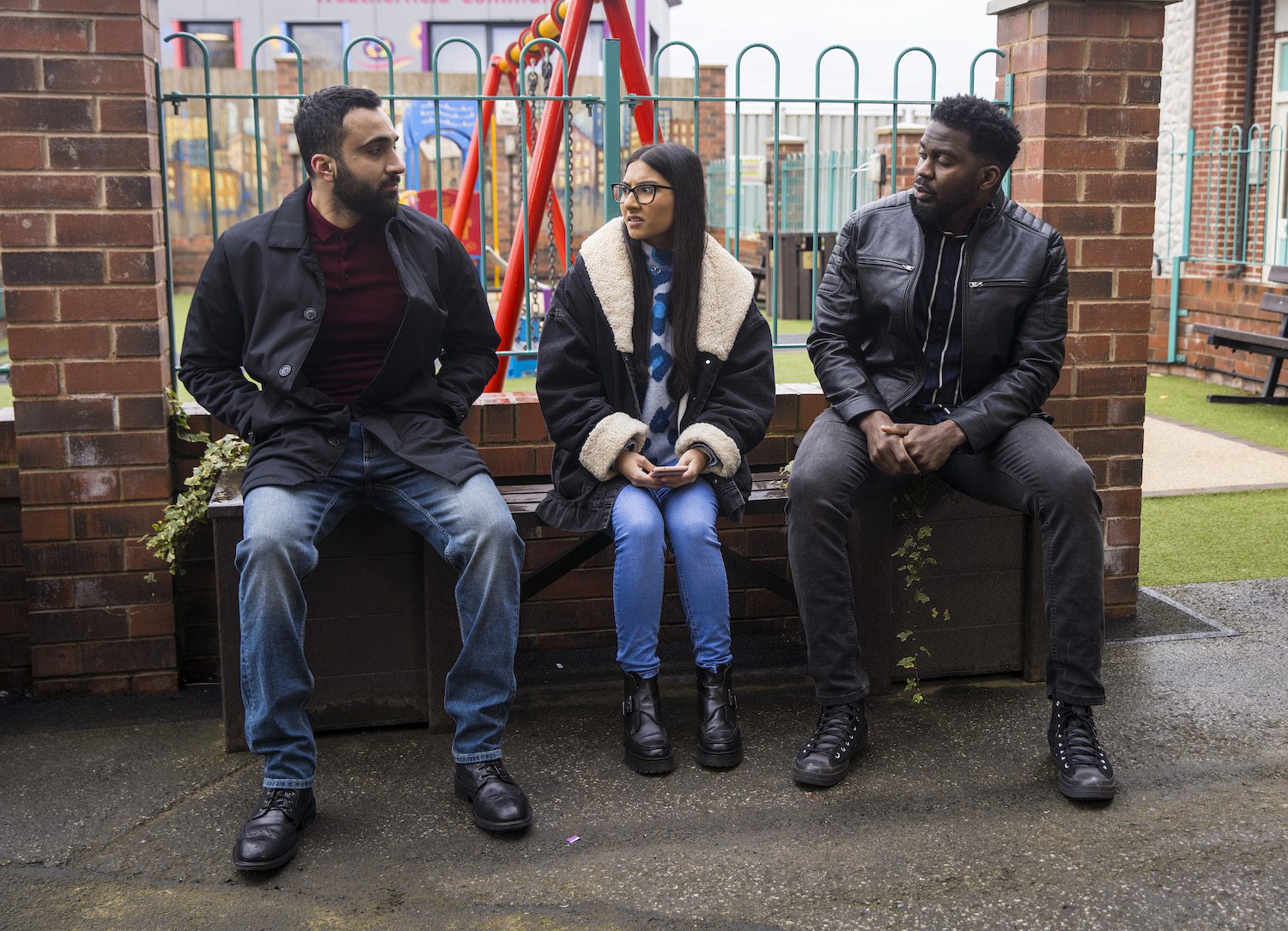 Corrie's Asha looks uncomfortable as two men sit either side of her in the precinct