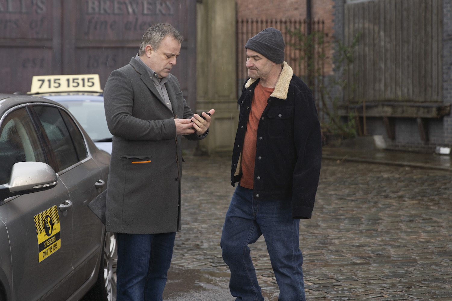 Coronation Street: Steve and Tim look annoyed as Steve looks at his phone