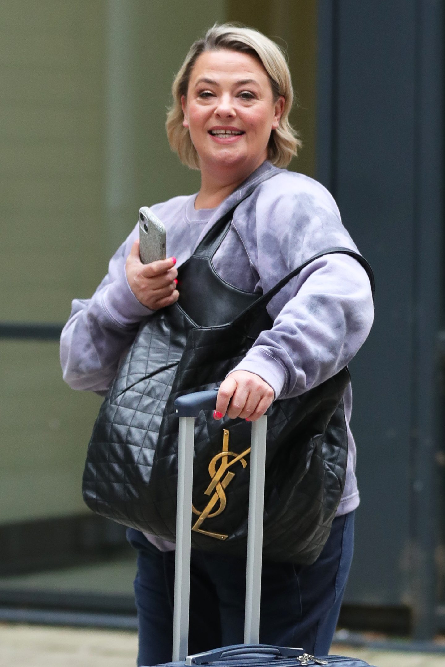 Lisa Armstrong dragging a suitcase and smiling