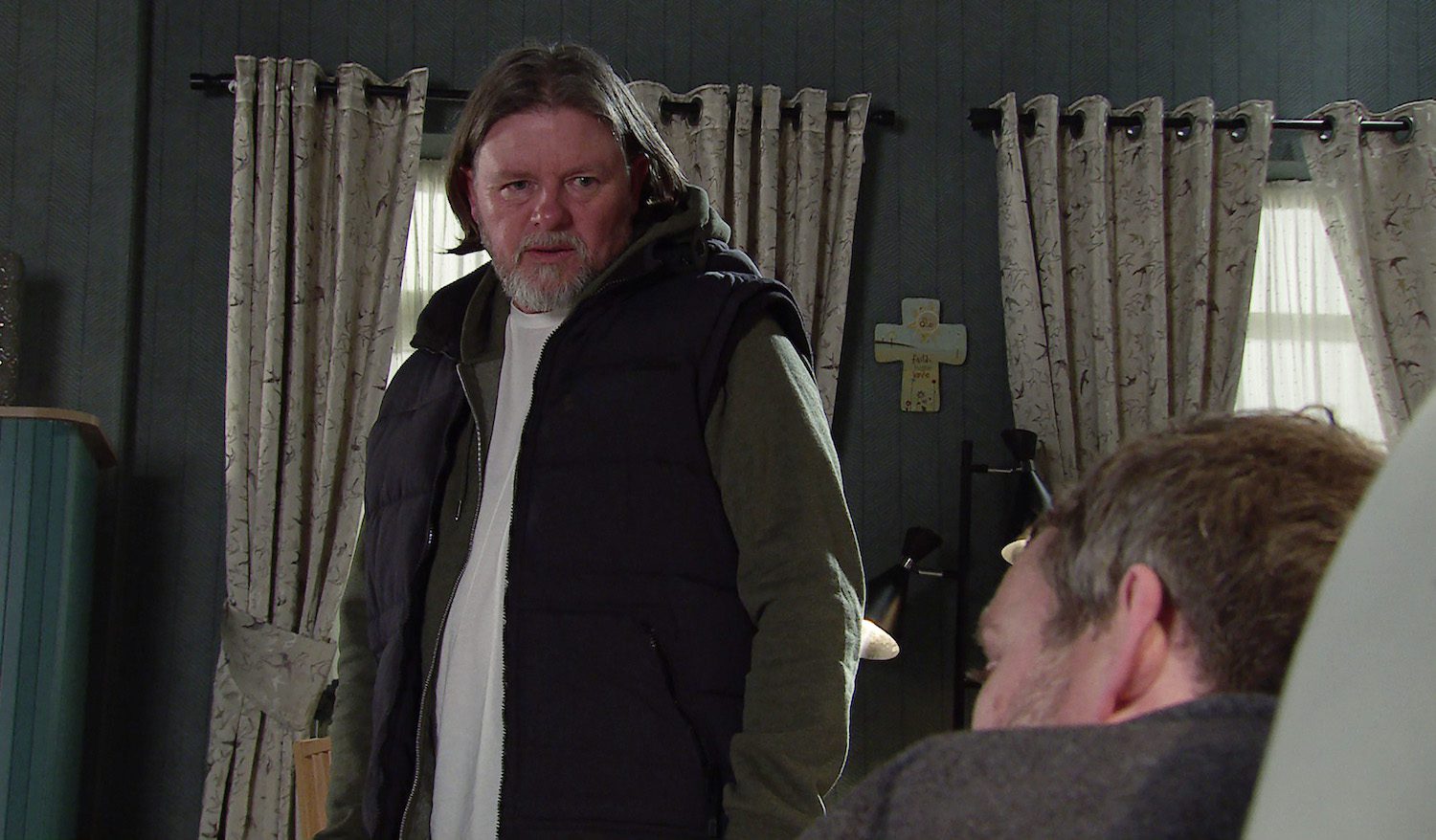 Denny looks at Paul slumped on the sofa in Corrie