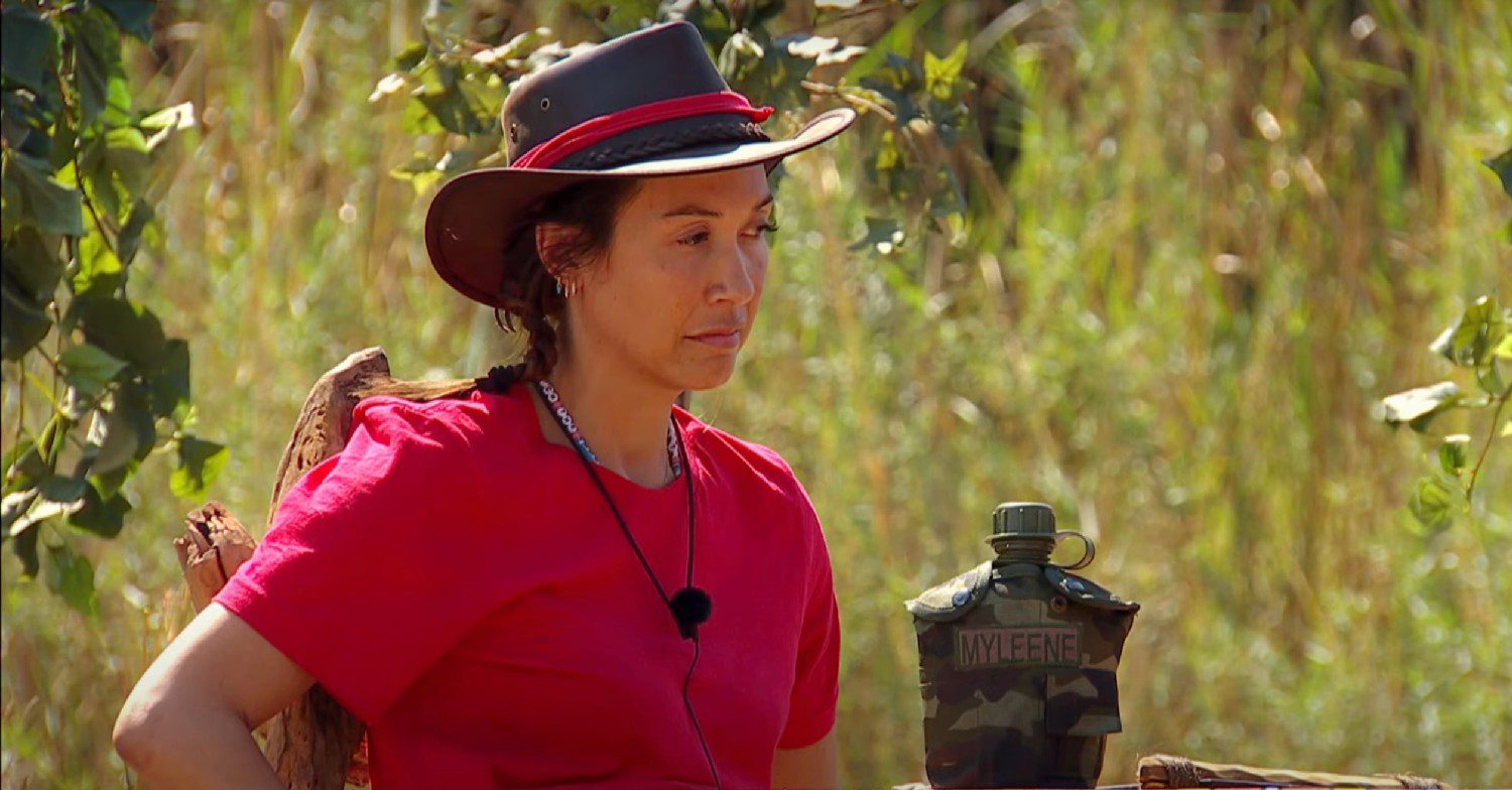 Myleene Klass in a hat and red shirt looking down on I'm A Celebrity South Africa 