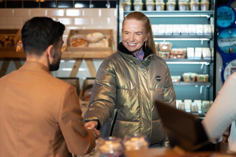 Bianca Jackson smiles and shakes Vinny Panesar's hand in the Minute Mart