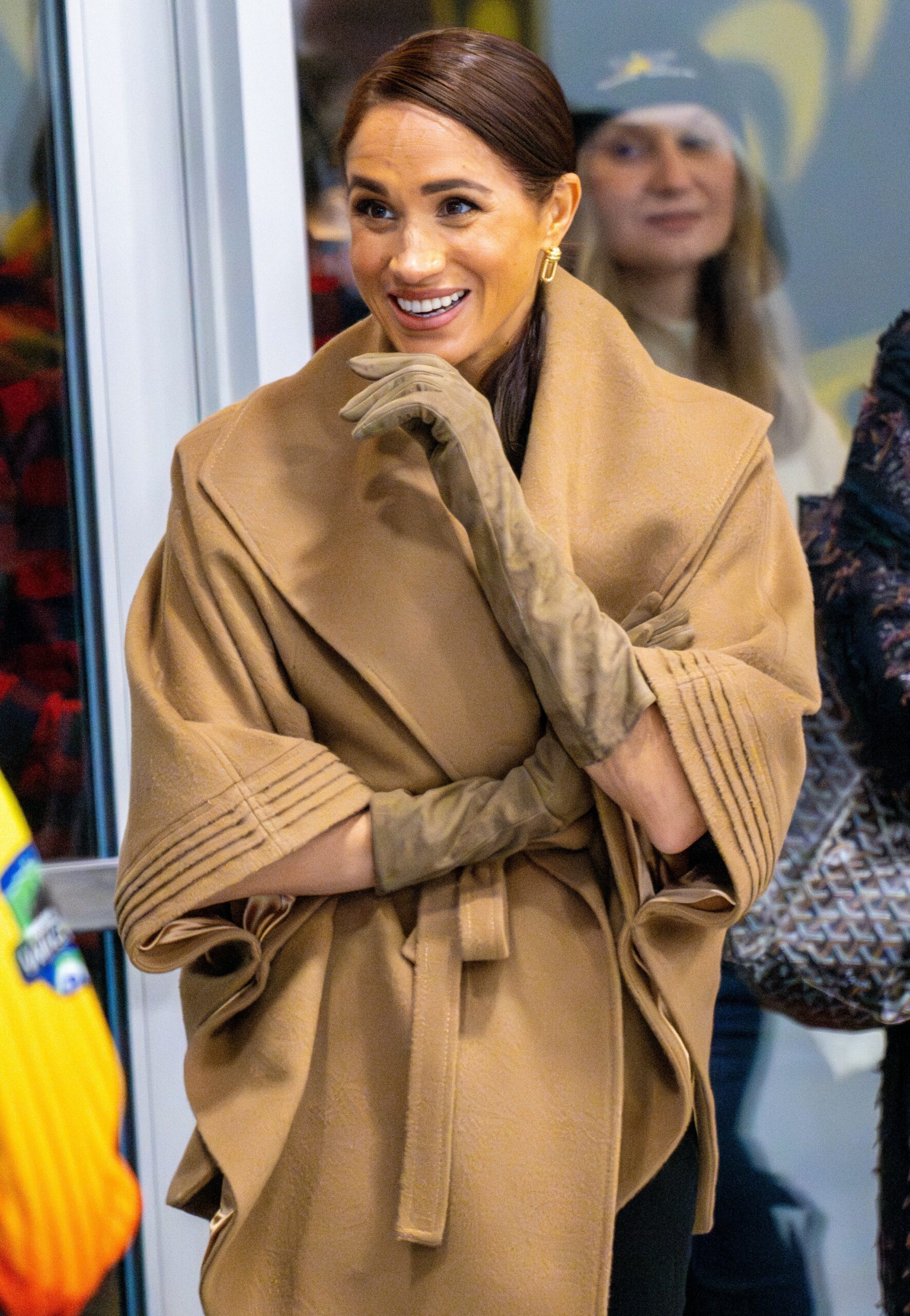 Meghan Markle smiling in beige jacket at event