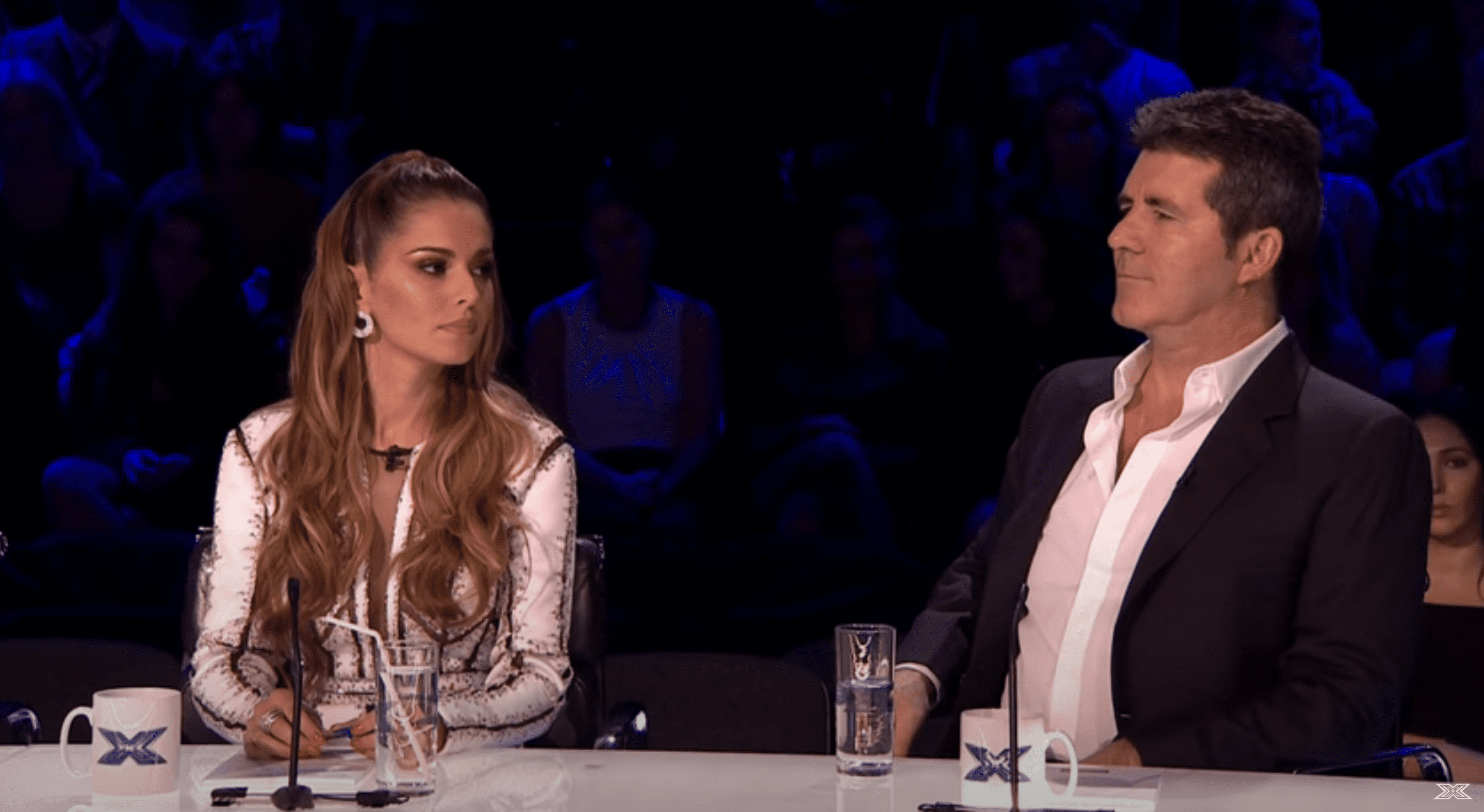 Cheryl Tweedy and Simon Cowell on the X-Factor, sat on the panel looking at each-other