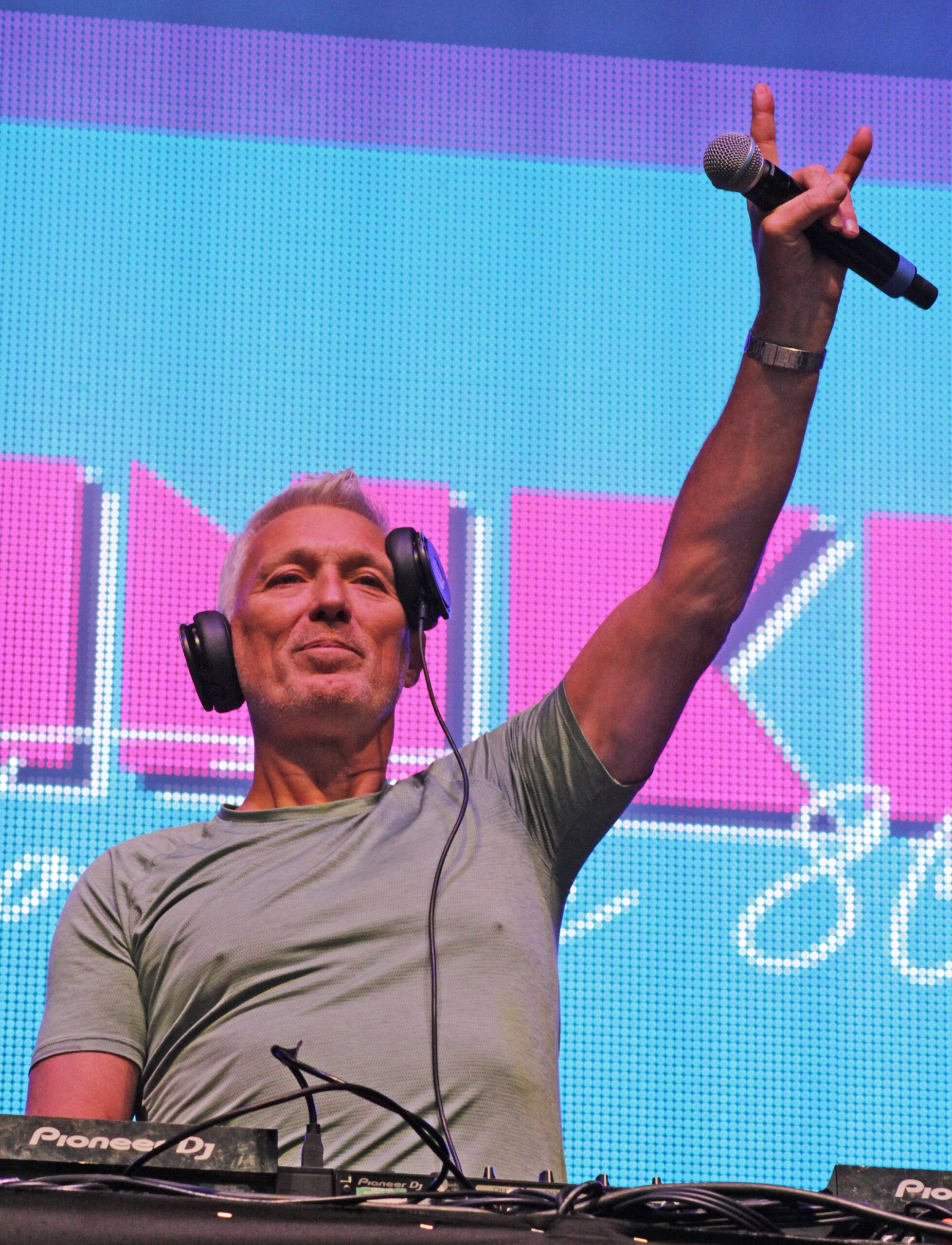 Martin Kemp holding a microphone while DJing on stage
