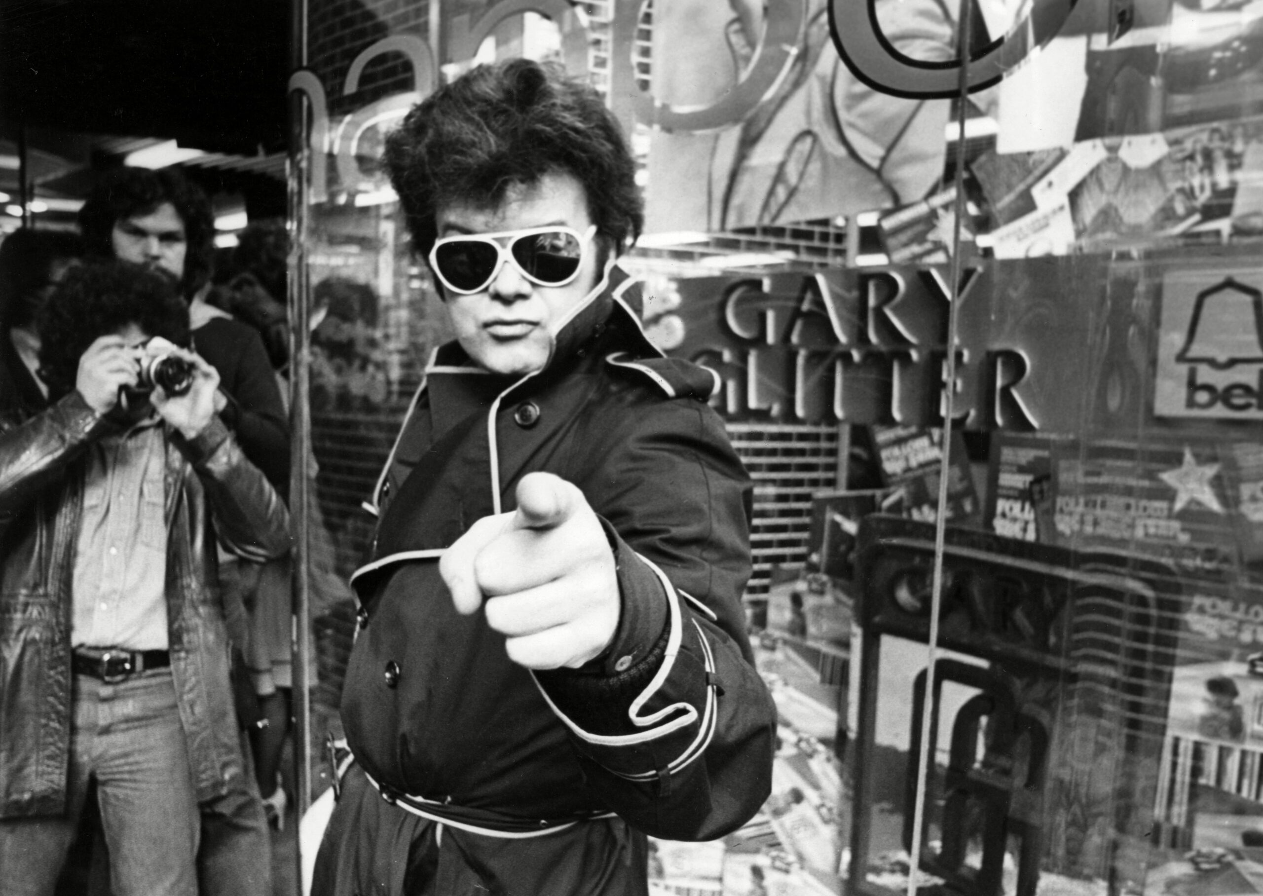 Gary Glitter in aviator sunglasses pointing at camera