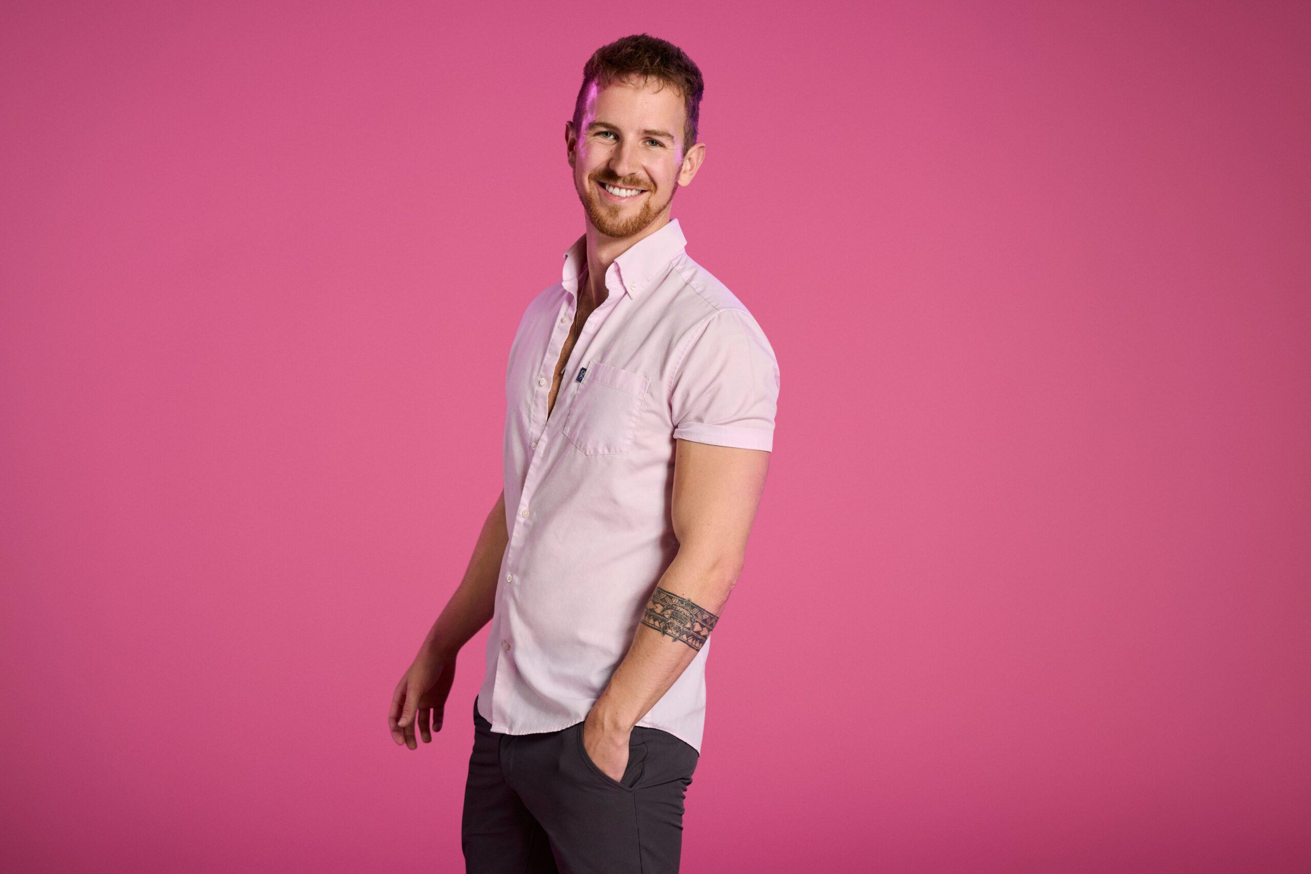Love Triangle contestant Dan poses in front of a pink background