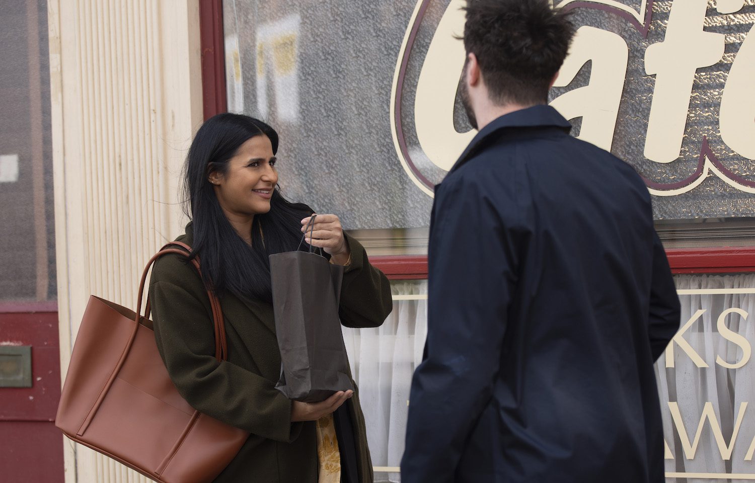 Alya smiles suspiciously as Adam gives her a bag in Corrie