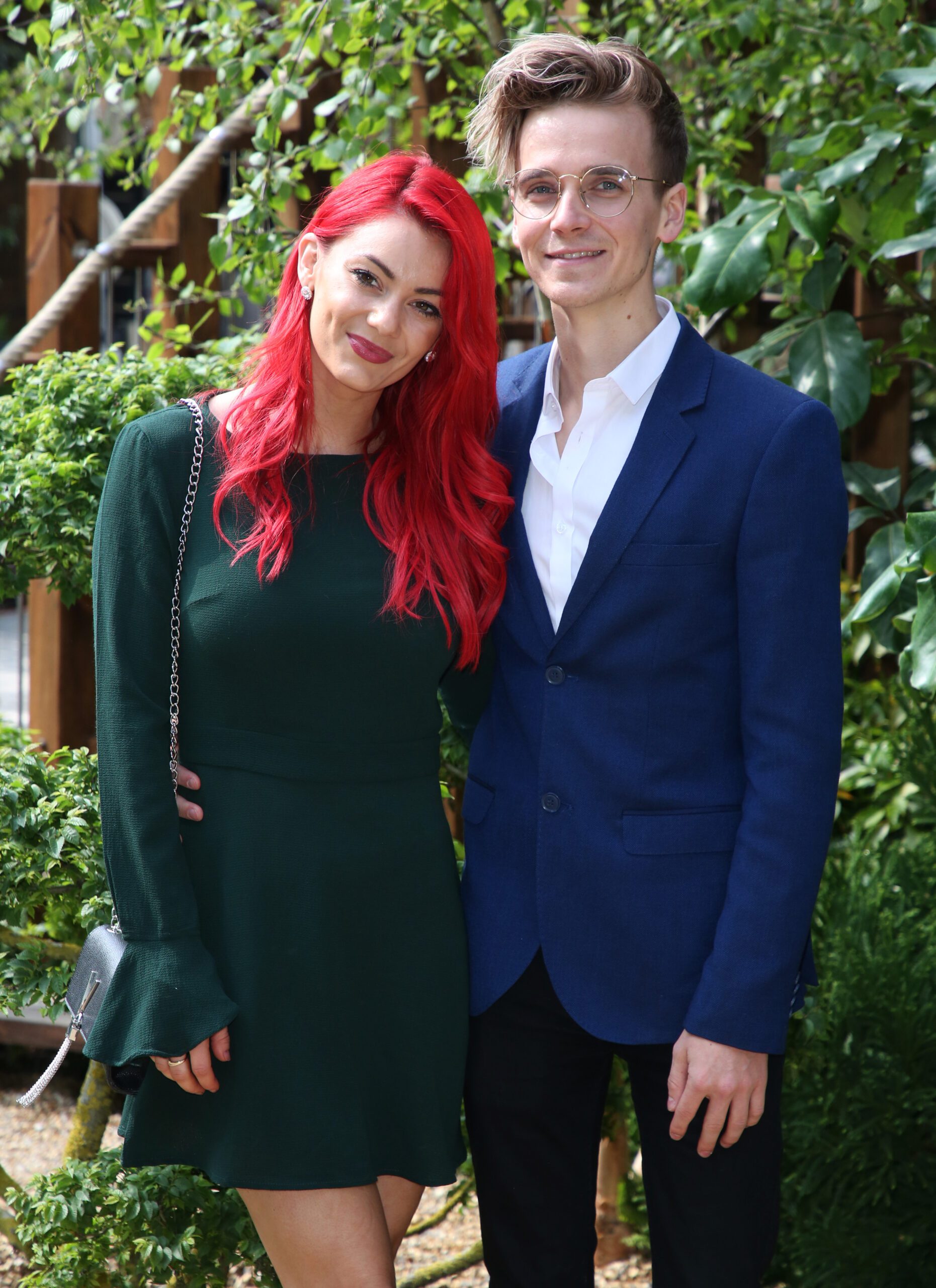 Dianne Buswell smiling beside Joe Sugg wearing green dress whilst Joe wears navy suit