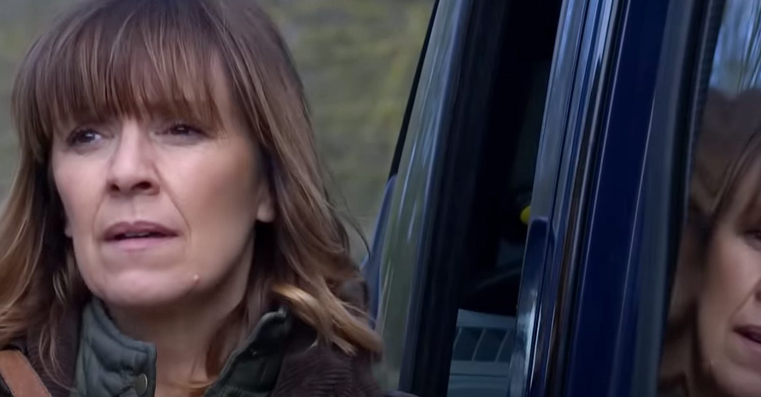 Emmerdale's Rhona is in deep thought, standing outside of the bus