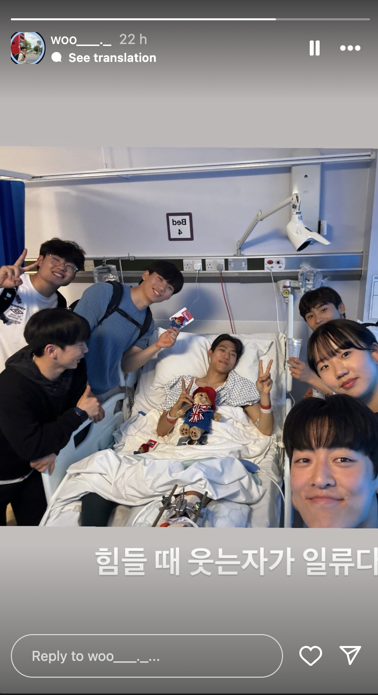 An image of Ssaulabi Performance Troupe in hospital visiting their injured member. All smiles and peace signs to the camera.