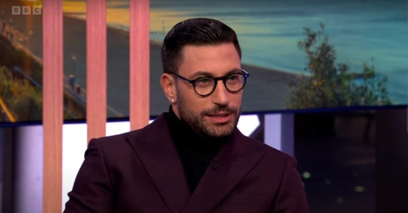 Giovanni Pernice wearing glasses and a turtle neck on The One Show
