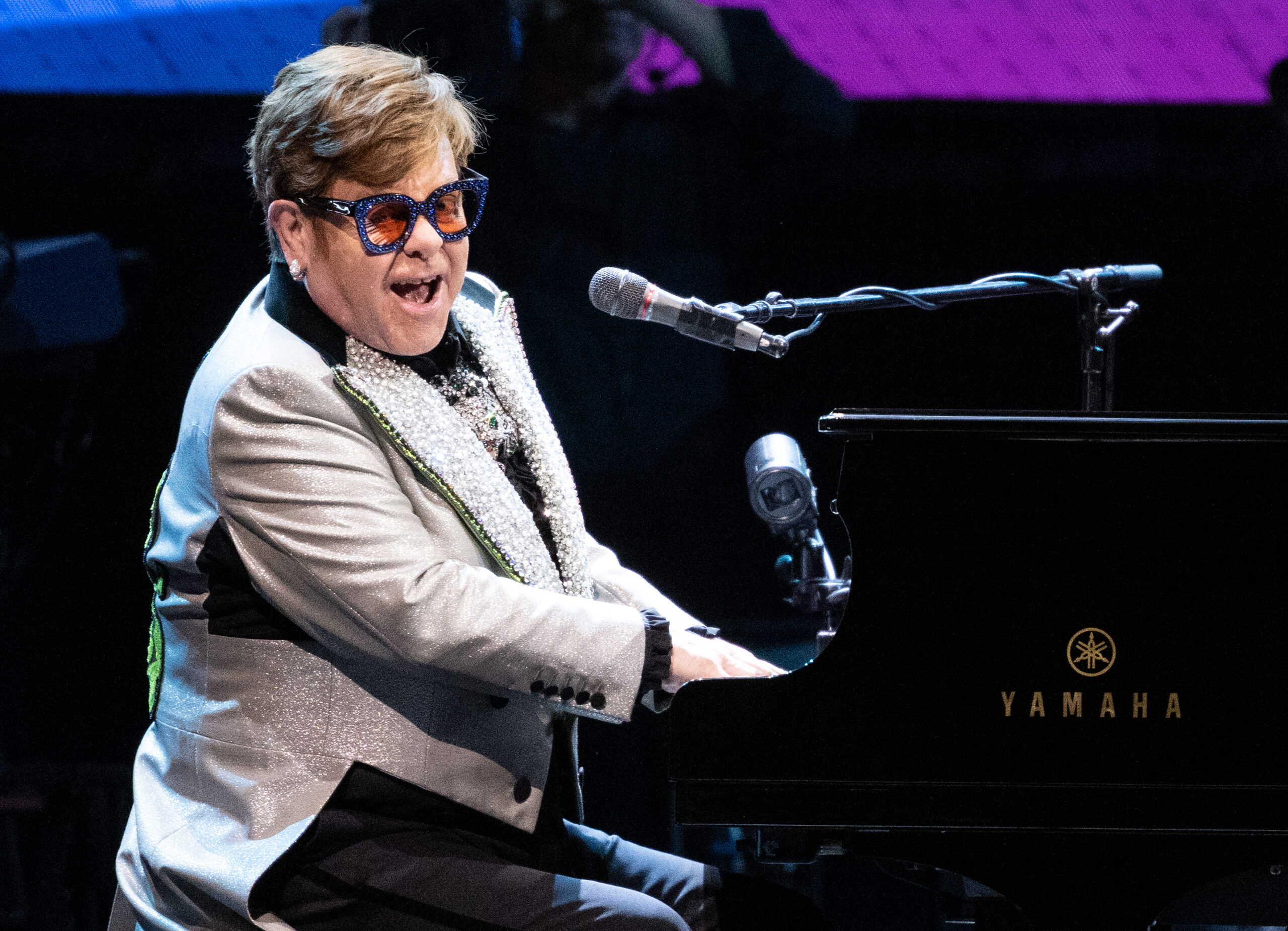 Elton John singing while playing piano on stage