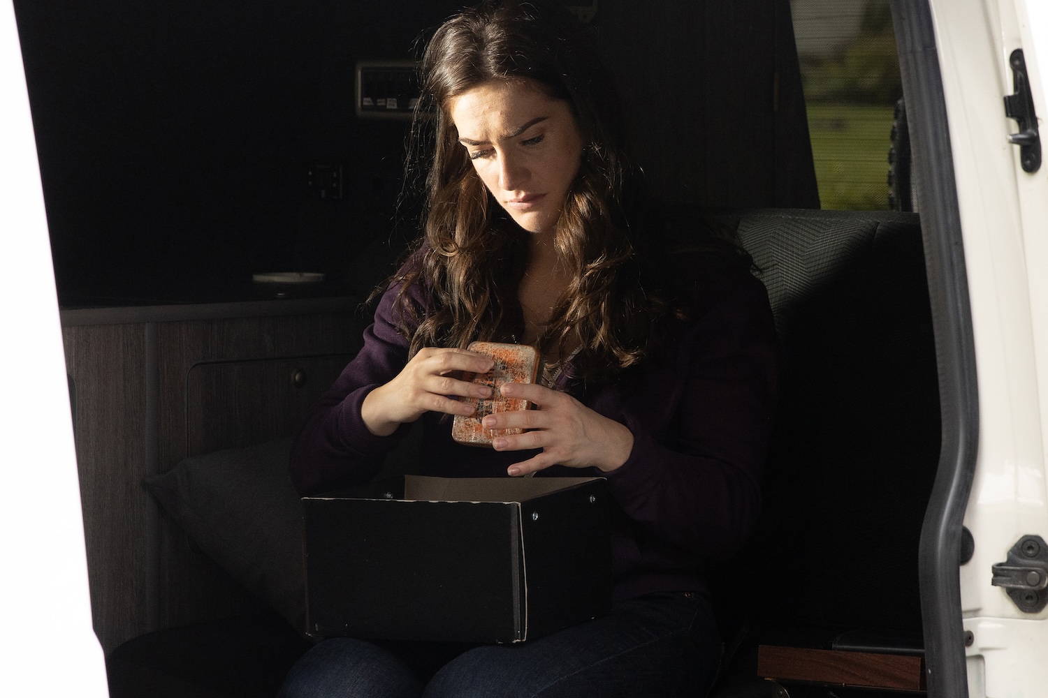 Victoria is looking at John's dog tag in the van