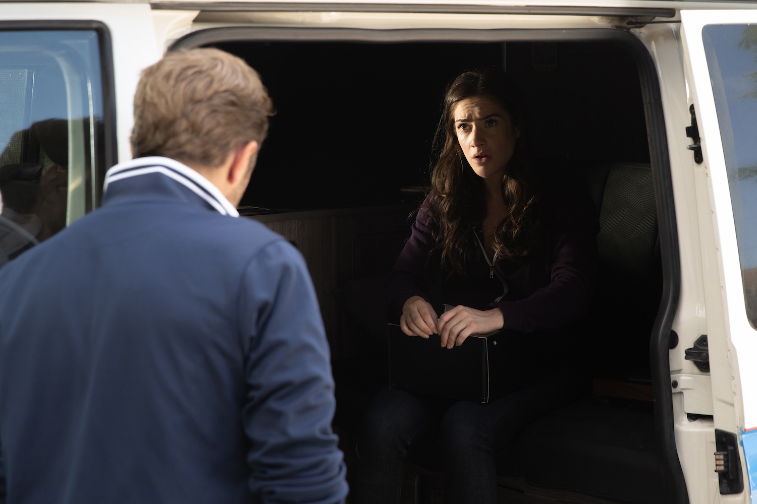 Victoria is looking at John's dog tag in the van
