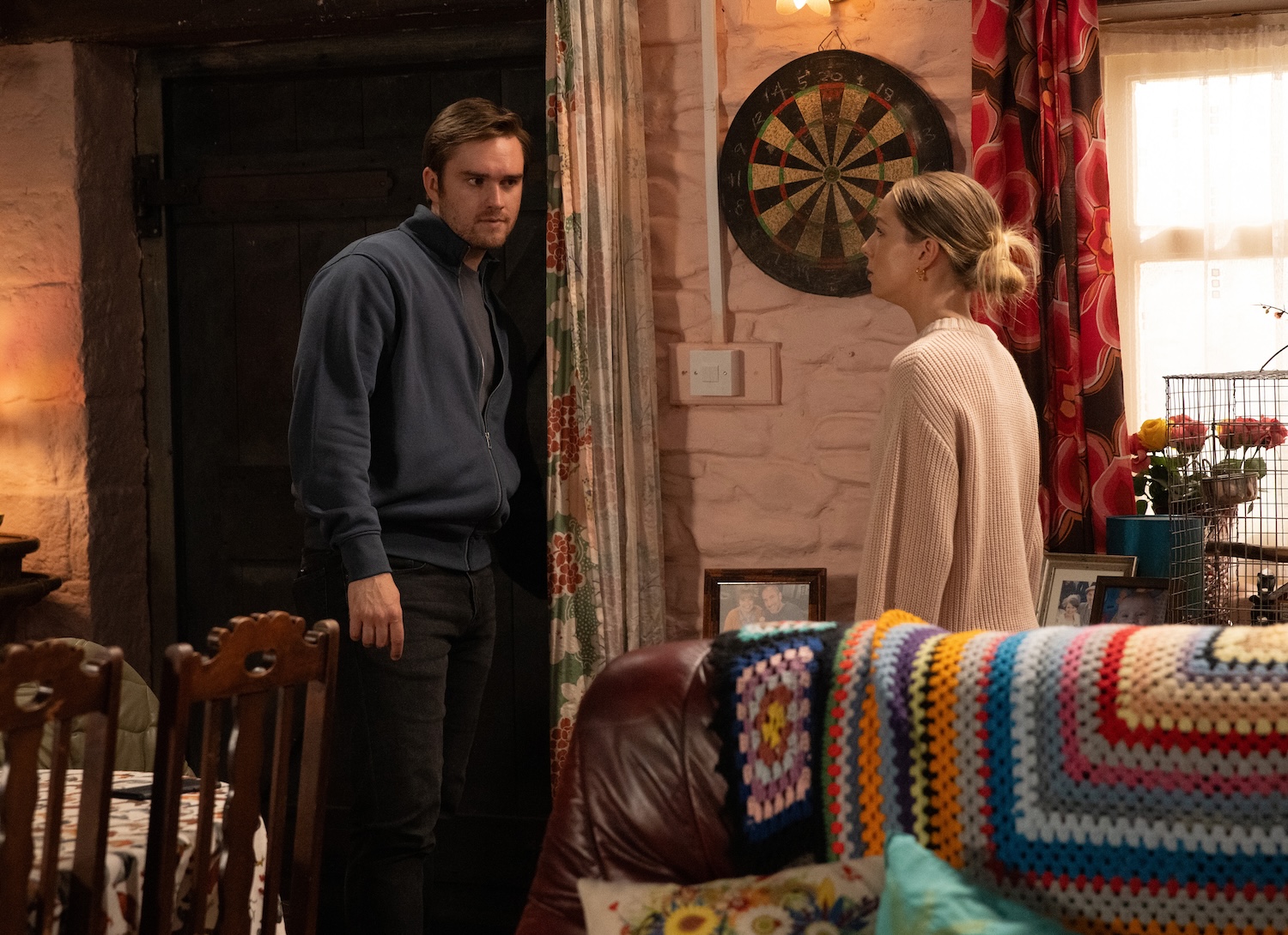 Tom standing in front of Belle on Emmerdale